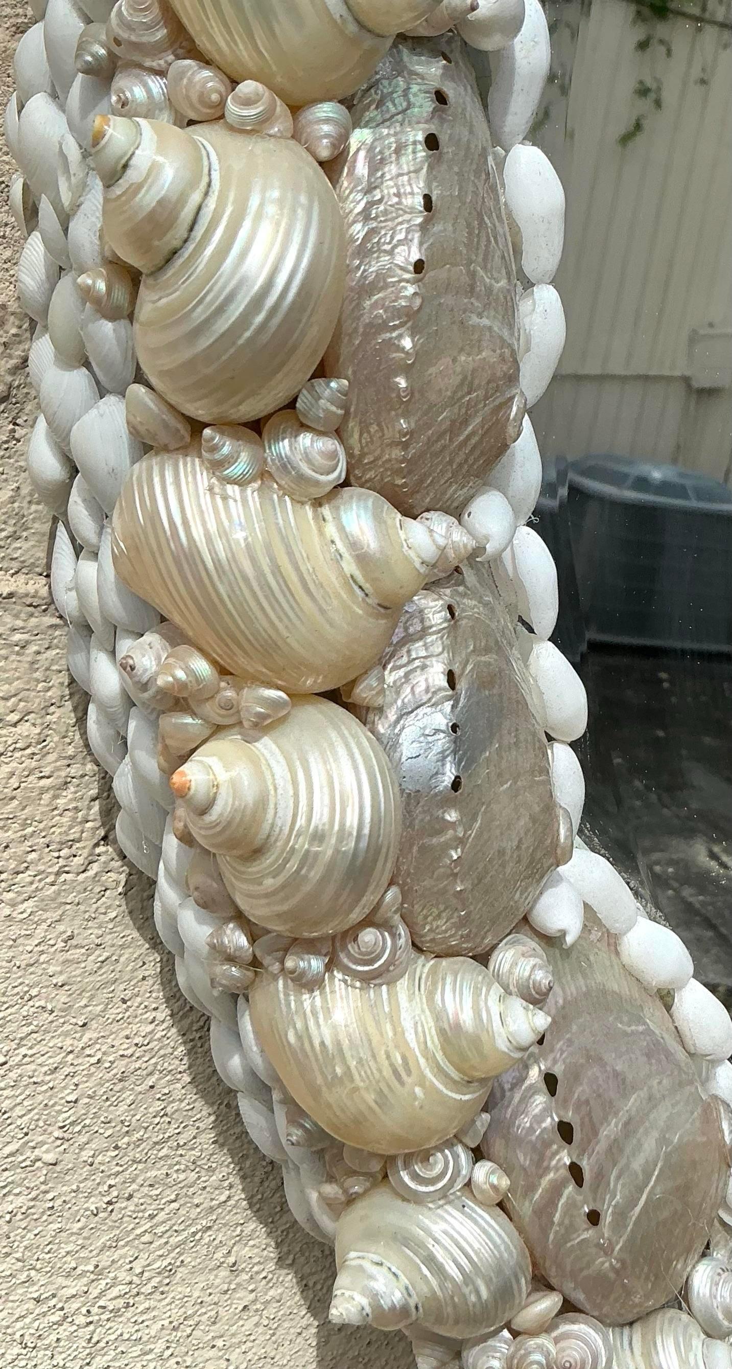 Este espejo ovalado costero vintage está bellamente incrustado con una variedad de conchas marinas naturales, creando un marco texturizado inspirado en la playa que captura la esencia del mar. Su diseño único y artesanal lo convierte en un llamativo
