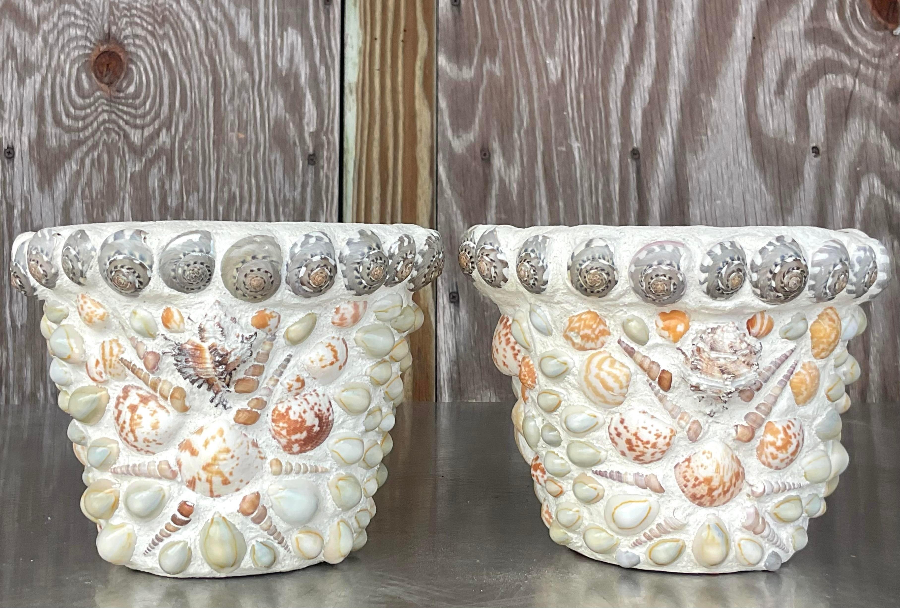 Capture the essence of coastal living with this pair of Vintage Coastal Shell Encrusted Terra Cotta Flower Pots. Crafted with Americana charm, these pots feature delicate shell accents, bringing seaside allure to your garden or indoor greenery with