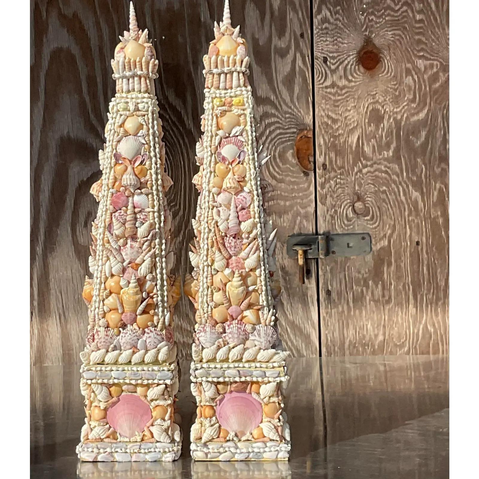 A stunning pair of vintage Coastal shell obelisks. Beautiful hand placed shells on a vintage set of wooden obelisks. Beautiful scale and coloration. Acquired from a Palm Beach estate.