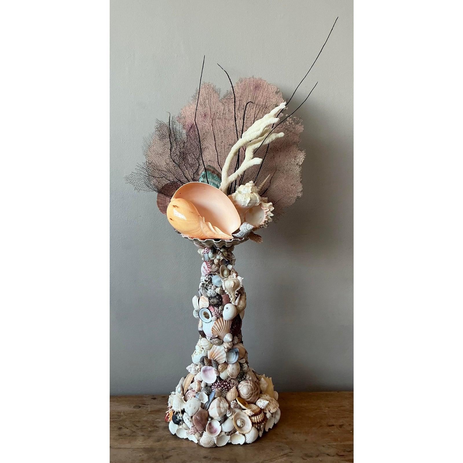 Evoca la serena bellezza dell'oceano con questa scultura totemica vintage di conchiglie e coralli. Realizzato meticolosamente a mano, questo pezzo unico presenta un'impressionante serie di conchiglie naturali e delicati rami di corallo, che