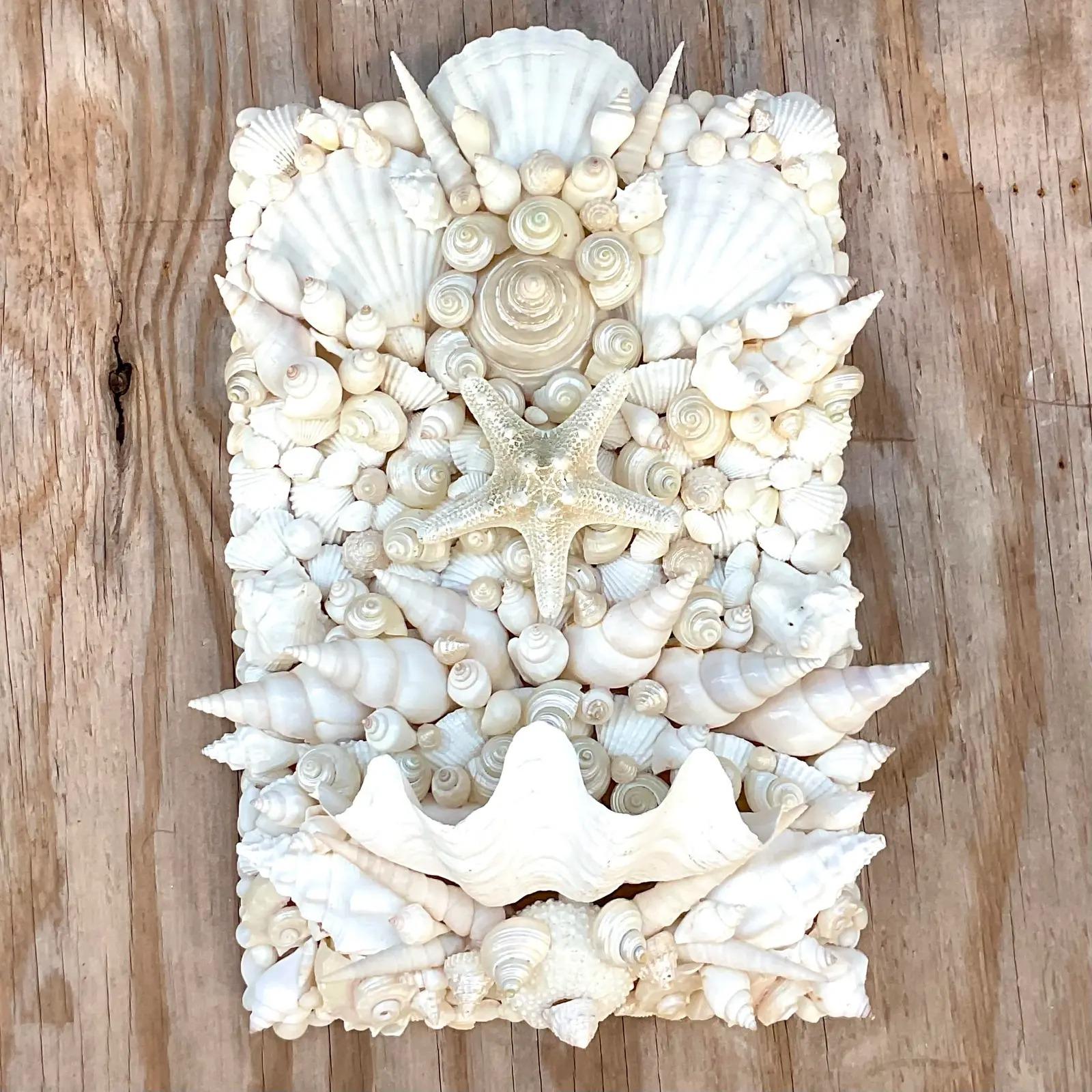 A stunning vintage Coastal shell wall sconce. Beautiful hand places shells with a large clam shell for a small votive. Two sconces available. Acquired from a Palm Beach estate.
