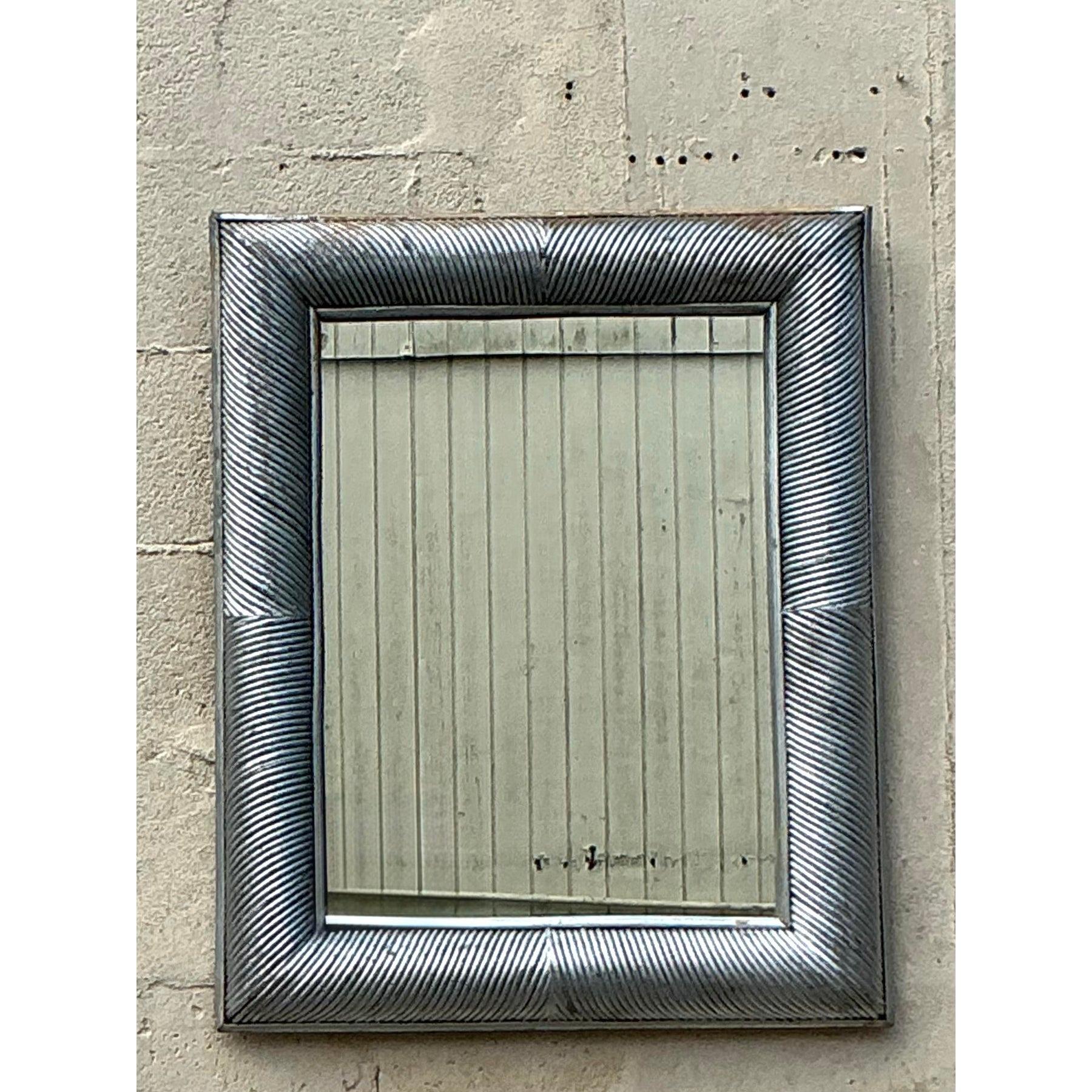 Ce miroir vintage saisissant met en valeur un cadre audacieux peint en roseau argenté avec une belle finition en détresse, ajoutant une touche d'élégance côtière et de charme rustique à n'importe quel espace. Les détails diagonaux complexes des