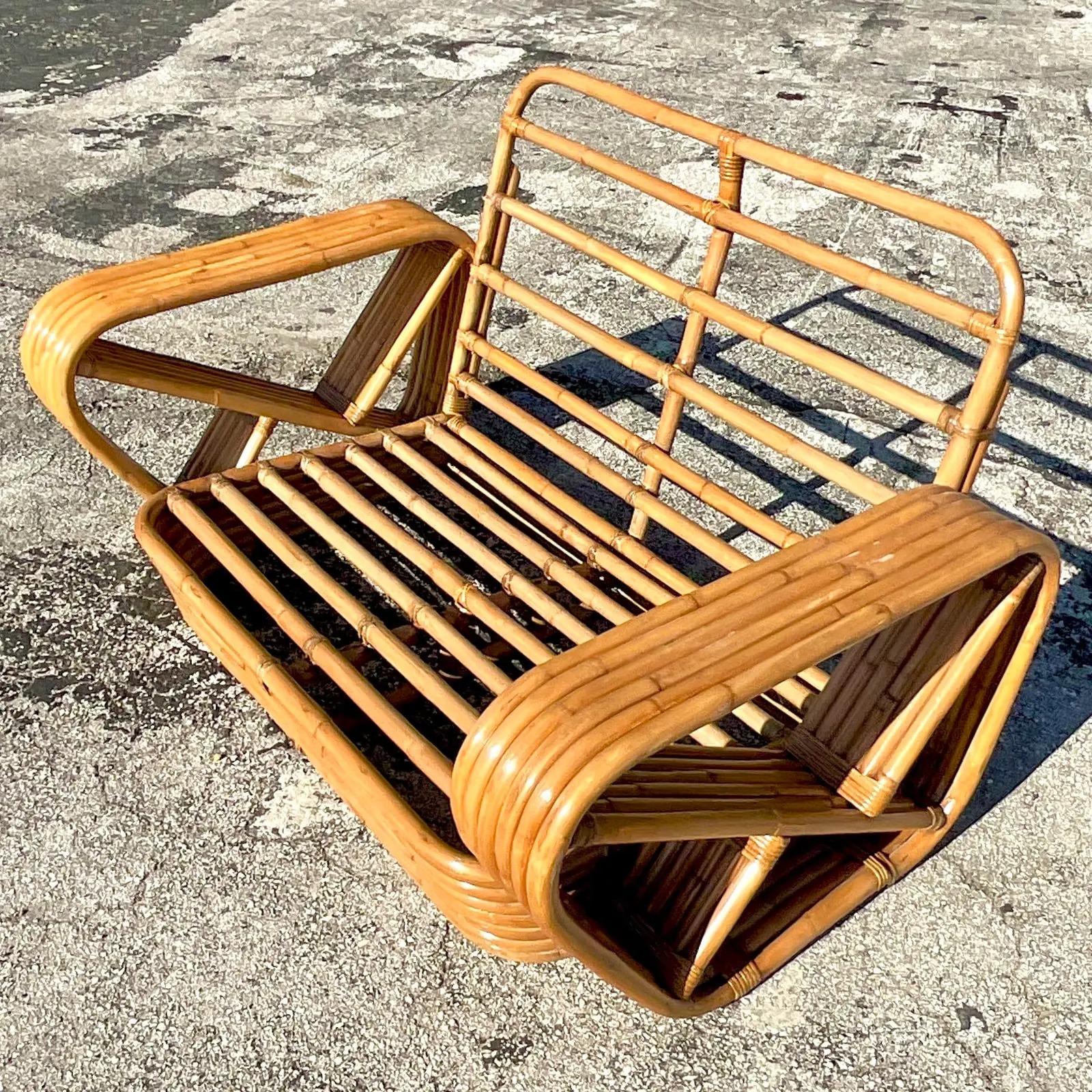 An incredible vintage Coastal loveseat After Paul Frankl. A six strand bent rattan in the classic Paul Frankl shape. In excellent condition. Acquired from a Palm Beach estate.