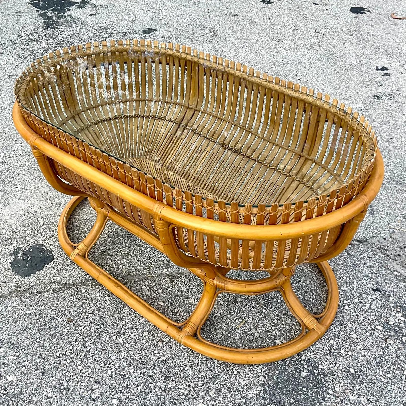 A fantastic vintage Coastal coffee table. Chic split rattan arranged in a slat design. Inset glass top. Acquired from a Palm Beach estate.