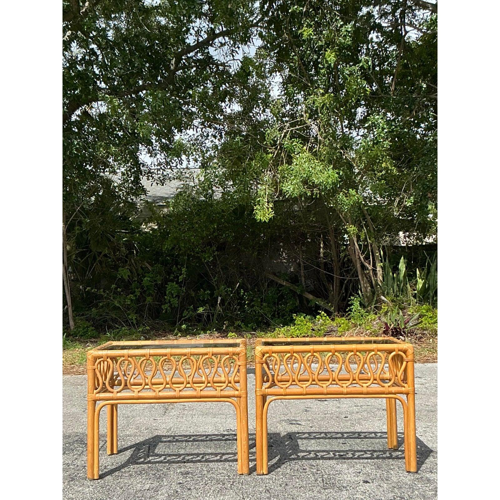 Dieses Paar verschnörkelter Rattan-Beistelltische im Vintage-Stil verleiht Ihrem Raum eine luftige, tropische Ausstrahlung. Mit ihrem wunderschön geschwungenen Rattangeflecht und den eingelassenen Glasplatten strahlen diese Tische luftige Raffinesse