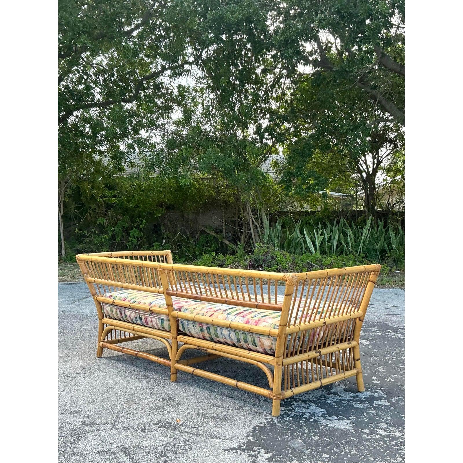 Die Eleganz der Küste wird mit diesem Bambus-Sofa im Vintage-Stil zum Ausdruck gebracht, das eine luftige Mischung aus natürlichen Materialien und entspannter Raffinesse darstellt. Mit seinen leicht angewinkelten Armlehnen, dem luftigen
