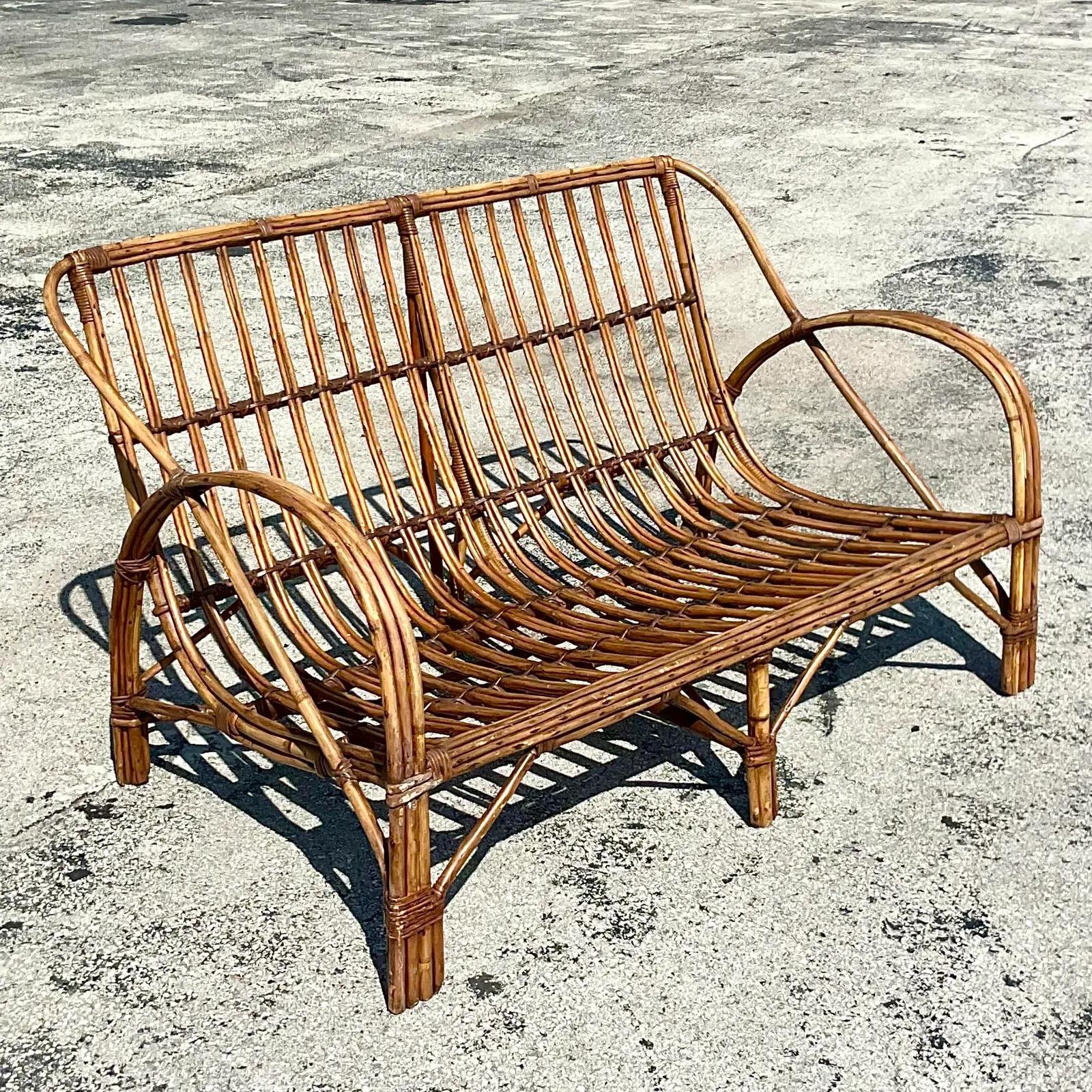 A chic vintage coastal sofa. A gorgeous stick rattan construction with an open weave design. Acquired from a Palm Beach estate.