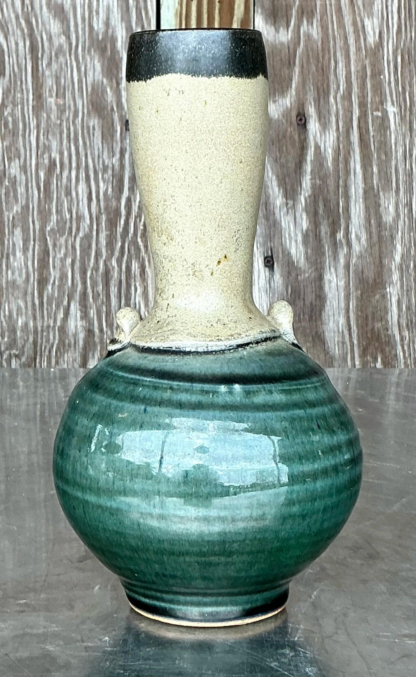 Aggiungi un tocco di charme artigianale al tuo spazio di ispirazione costiera con questo vaso a collo lungo dello Studio Pottery Vintage Coastal. Caratterizzato da un collo elegante e allungato e da una ceramica di ottima fattura, questo vaso