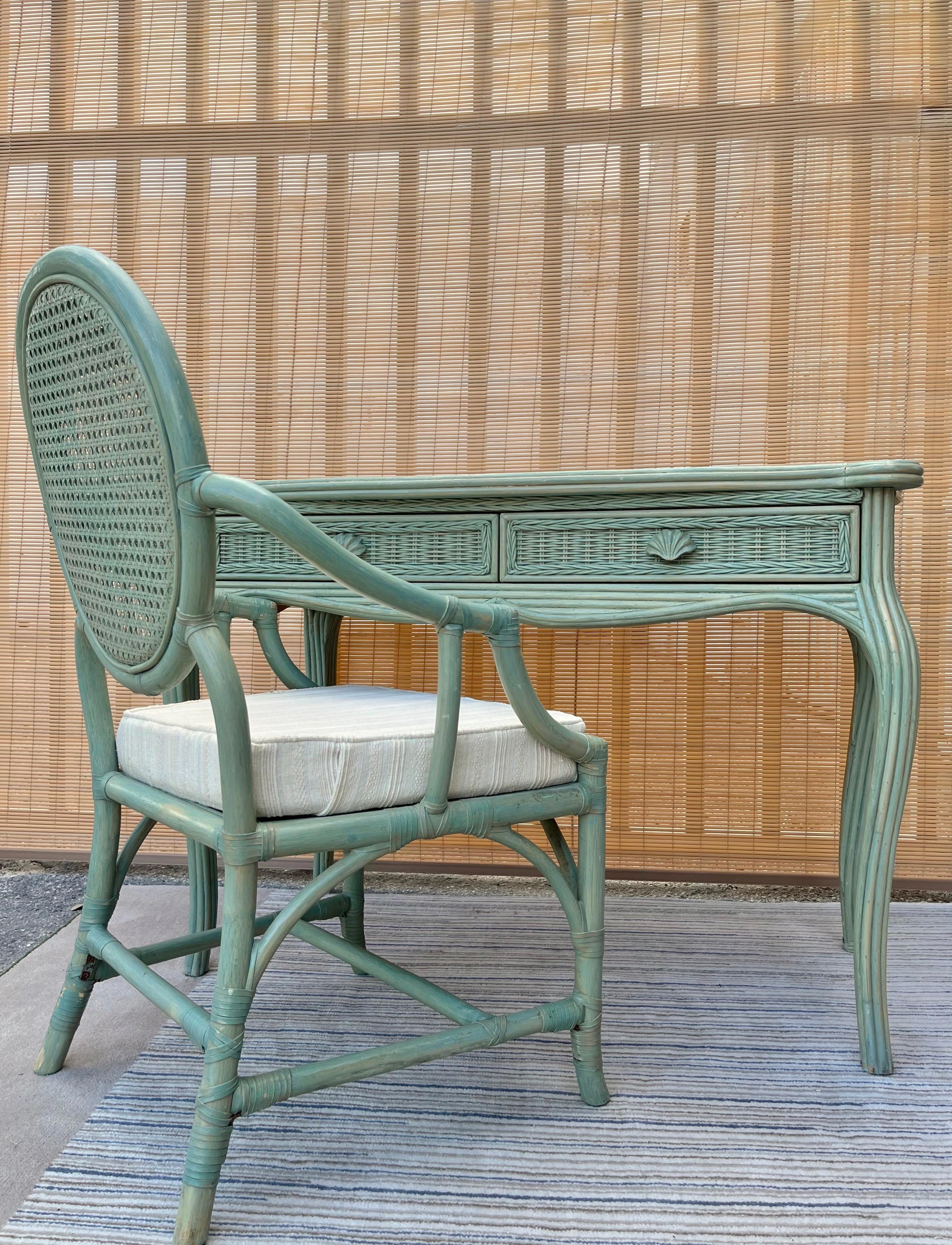 Vintage coastal style pencil reed and wicker vanity / writing desk with chair by Whitecraft Furniture. Circa 1980s 
The Vanity / Writing Desk features two drawers with hand carved seashell pulls, a removable glass top, and a unique washed pastel