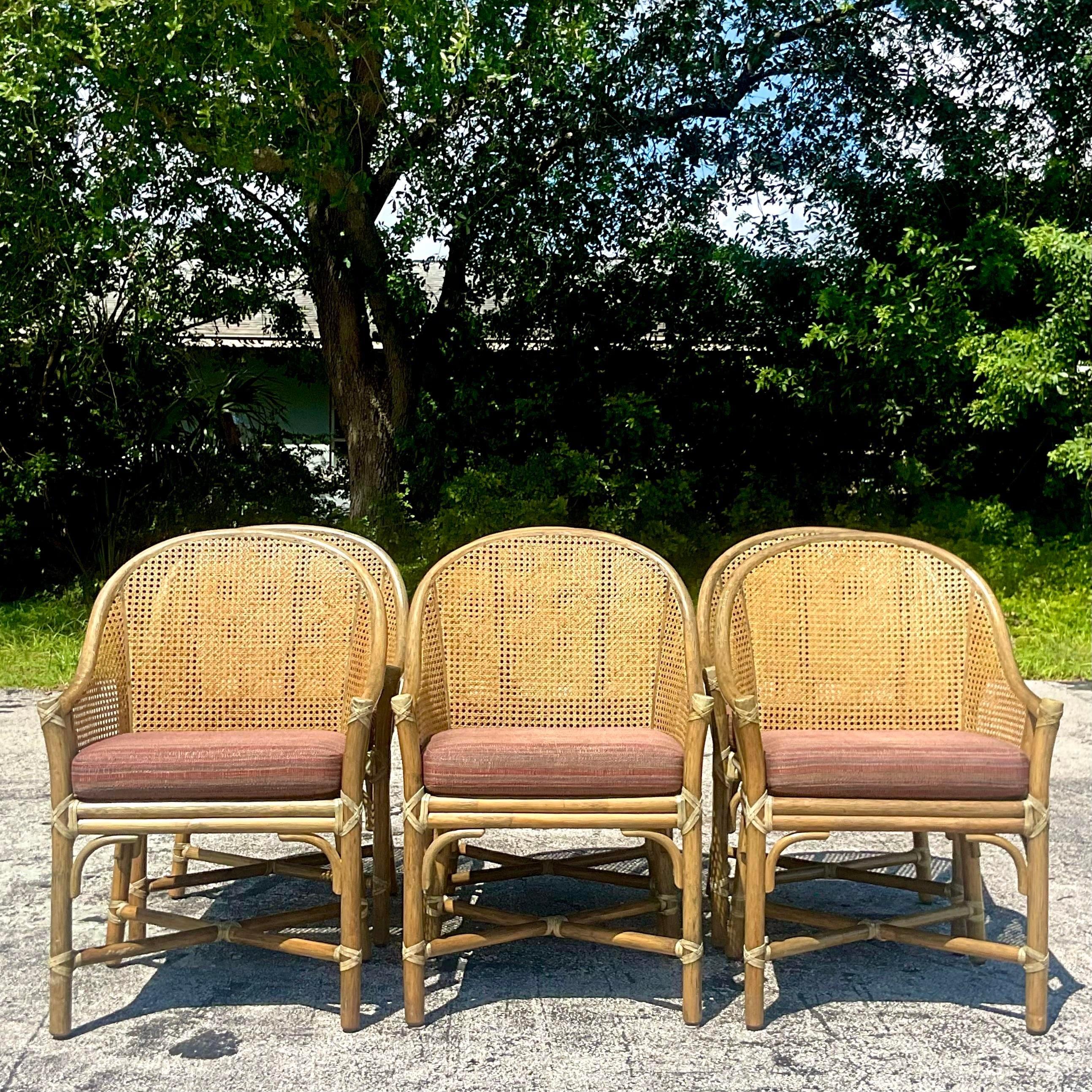 A fabulous set of vintage Coastal dining chairs. Made by the iconic McGuire group and tagged on the bottom. Chic bent rattan in a sloped arm design. Cane back seats sun perfect shape. Loose cushions in a tweed boucle. Acquired from a Palm Beach