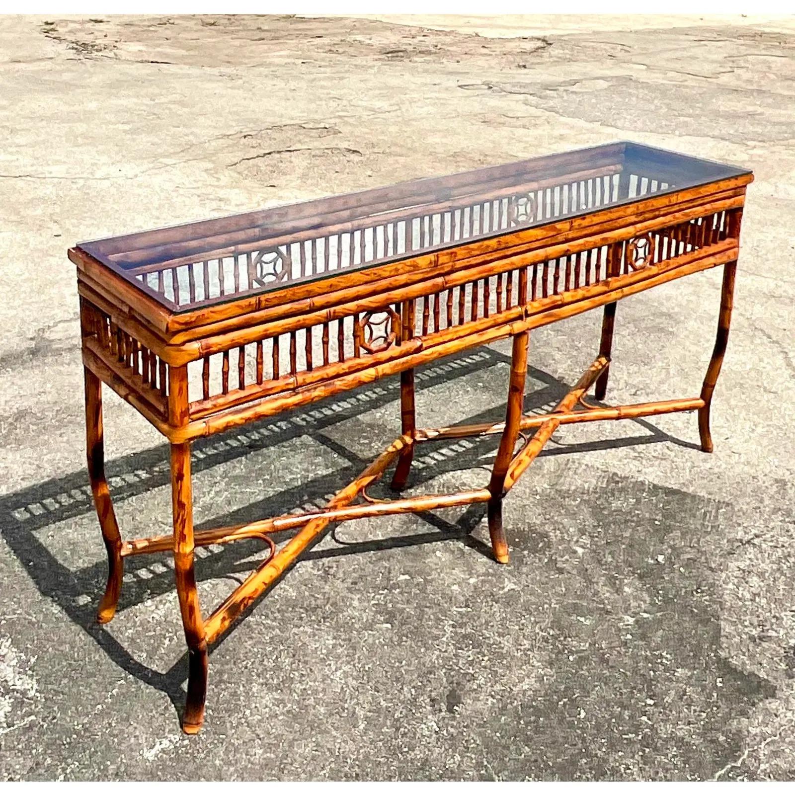 Fantastic vintage console table. Beautiful tortoise shell finish rattan in a chic open design. Inset glass top. Acquired from a Palm Beach estate.