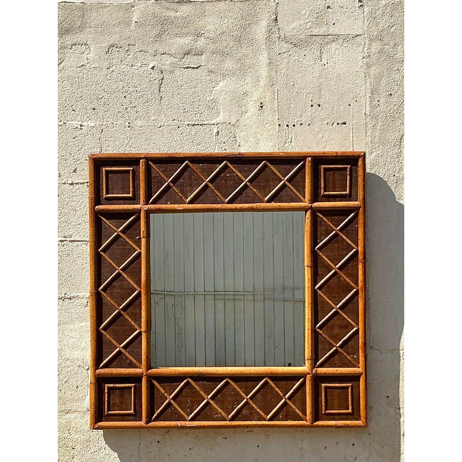Infondi nel tuo spazio il fascino tropicale di questo splendido specchio in rattan vintage. Caratterizzato da un audace design a traliccio con motivi geometrici quadrati e a rombi, questo grande specchio da parete quadrato è incorniciato in rattan