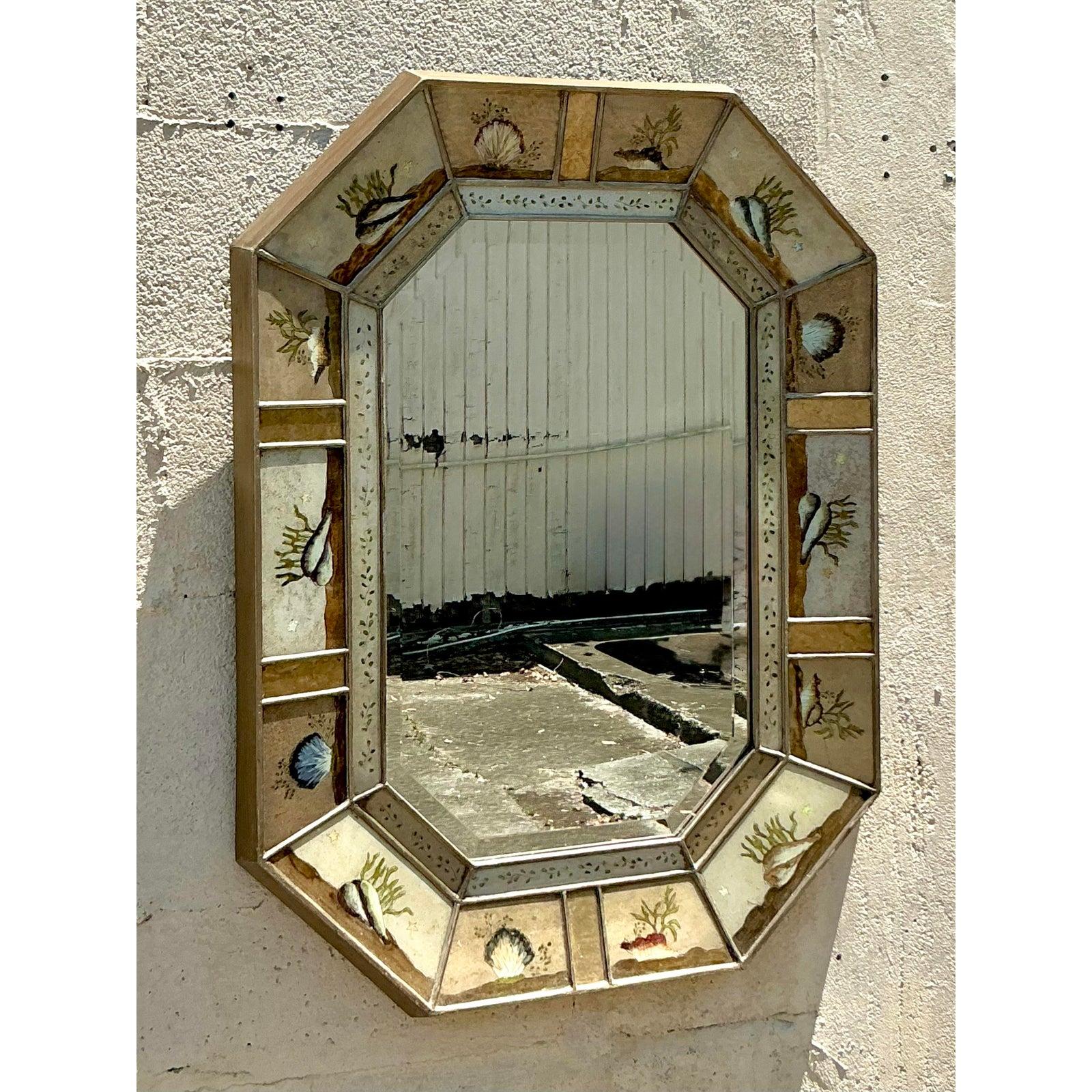 Cattura l'incantevole bellezza delle profondità oceaniche con questo squisito specchio ottagonale vintage. Il pezzo presenta un'affascinante bordura di pannelli eglomise dipinti a mano, ognuno dei quali raffigura affascinanti motivi sottomarini come
