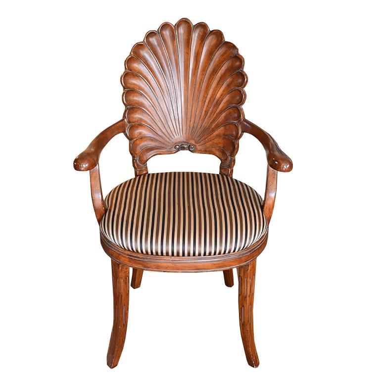 An exquisitely carved wood Venetian shell back armchair. This gorgeous piece is carved of rich dark wood. The back resembles a Venetian Grotto shell. It has paw arms and splayed legs. It is upholstered in a silky stripe fabric in cream, black, and