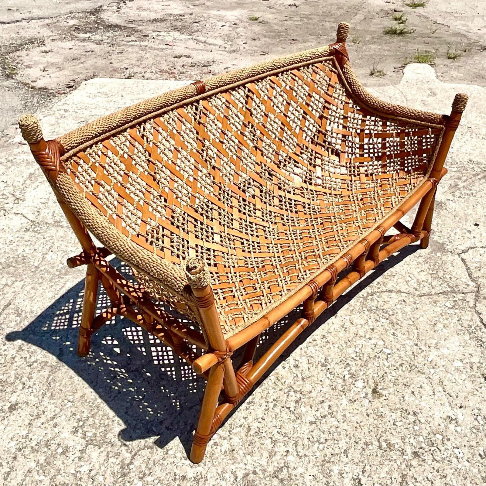 Fantastic vintage Coastal sofa. A chic sling design with woven leather and jute straps. Rests in a thick rattan frame. A super sexy shape. Acquired from a Palm beach estate.