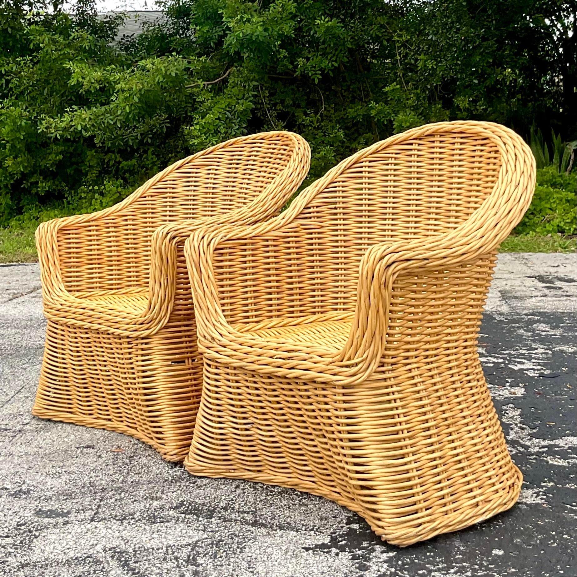 A fabulous pair of vintage Coastal lounge chairs. A chic woven rattan with a heavy trim. Acquired from a Palm Beach estate.