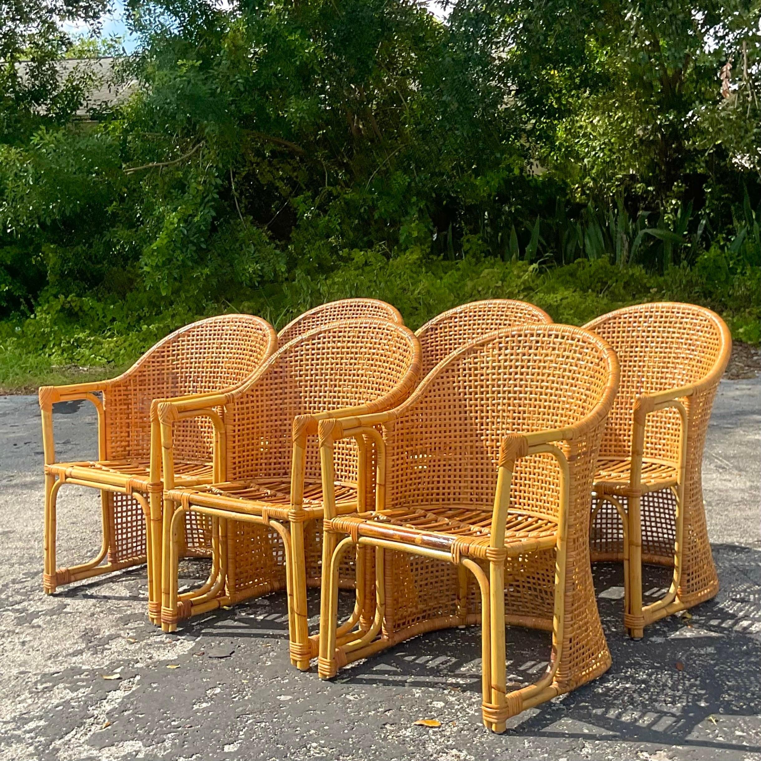 A fantastic set of six vintage Coastal dining chairs. A chic woven rattan frame with a wrap around barrel back. In excellent condition and a beautiful patina from time. Acquired from a Palm Beach estate.