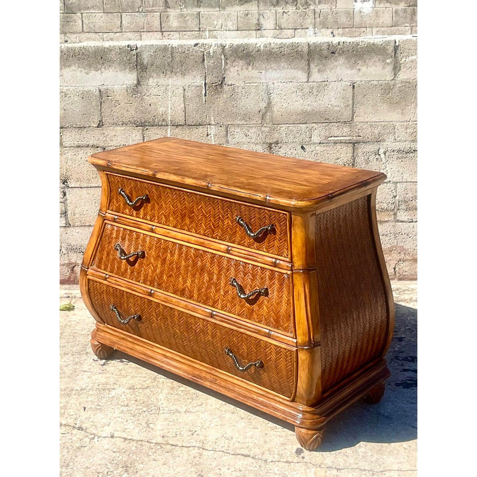 Fantastic vintage Coastal carved bamboo chest of drawers. A deep rich brown cabinet with inset woven rattan panels. A chic curved shape with beautiful ornate hardware. Acquired from a Palm Beach estate.