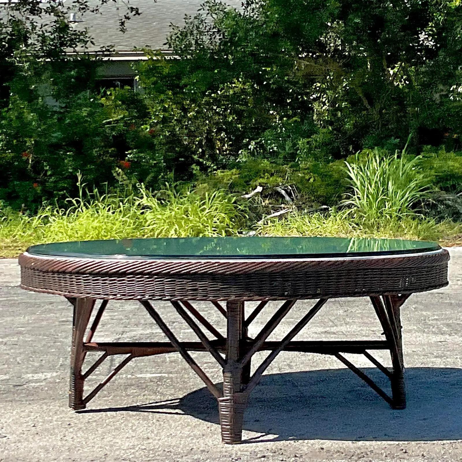 A charming vintage Coastal coffee table. A restored period piece with a new inset upholstered panel in a chic herringbone weave. Glass rests on top. Acquired from a Palm Beach estate.