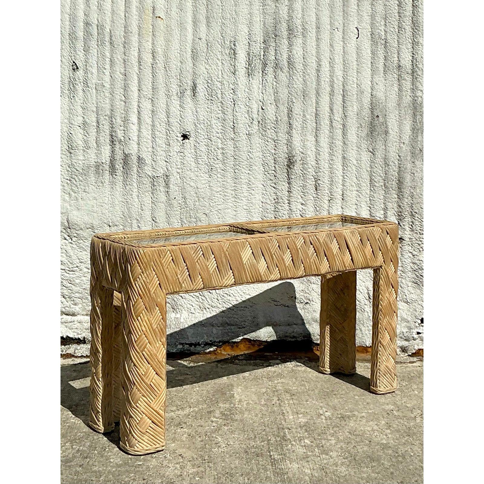 Dieser atemberaubende Konsolentisch aus geflochtenem Vintage-Rattan im Küstenstil bringt organische Eleganz und Struktur in jeden Raum. Mit einem komplizierten handgewebten Muster versehen, verkörpert dieses Stück zeitlose Handwerkskunst und
