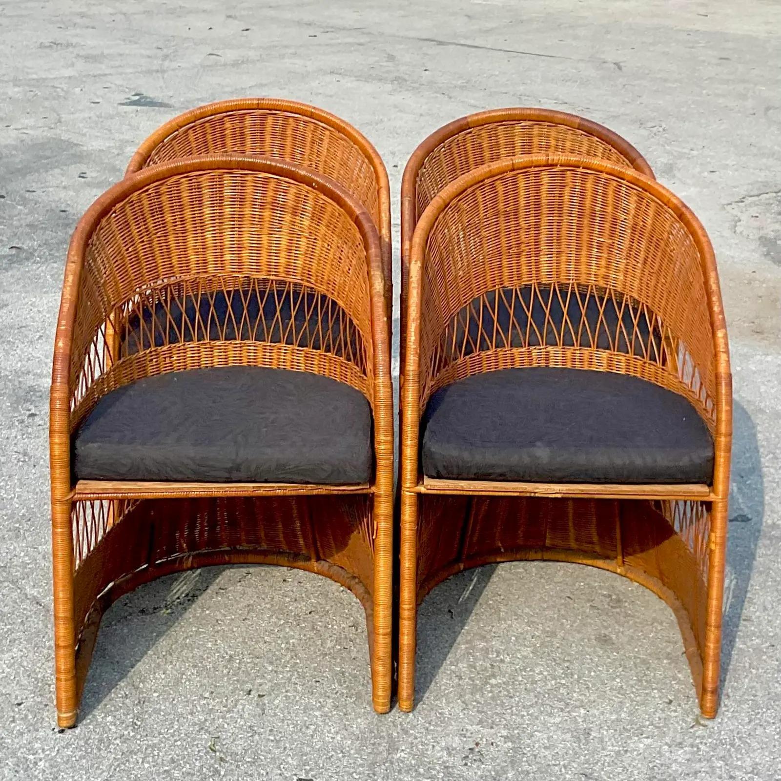 A fabulous set of four vintage Coastal dining chairs. Chic woven rattan chairs in a sexy tub shape. Open areas in the weave to let light pass through. Acquired from a Palm Beach estate.
