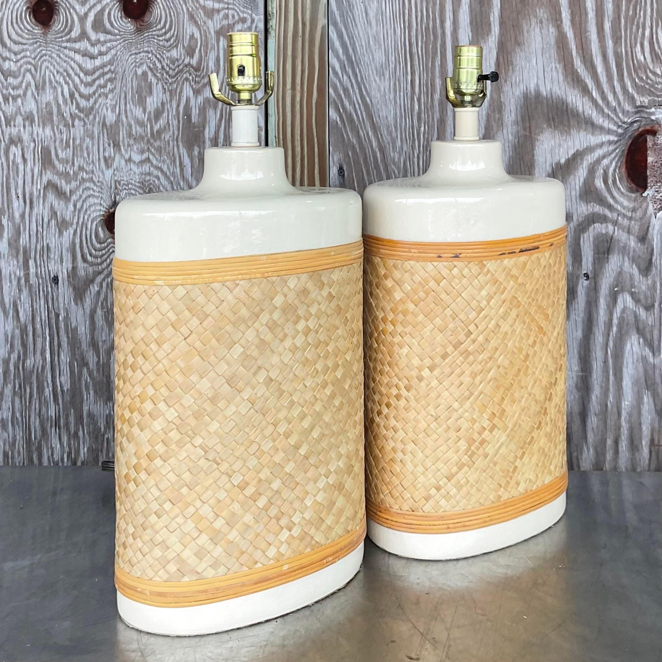 A fabulous pair of Coastal table lamps. Chic panels of woven rattan that are wrapped around a glazed ceramic lamp. Simple and cool. Acquired from a Palm Beach estate.