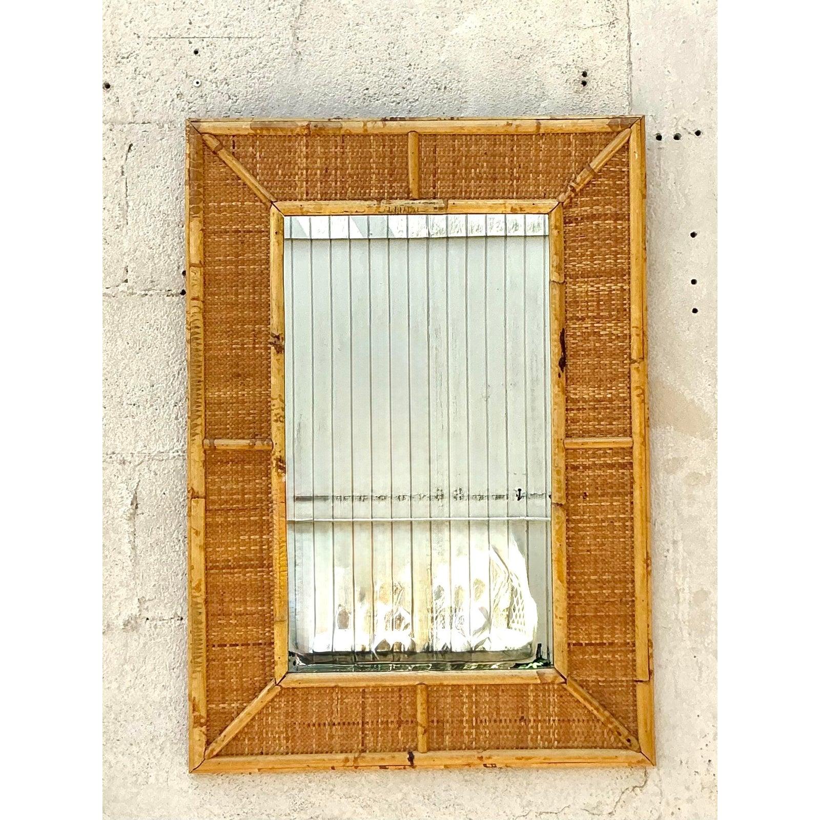 Apportez une touche de chaleur naturelle et de texture artisanale à vos murs avec ce miroir vintage classique en rotin. Cette pièce magnifiquement fabriquée présente un cadre trapézoïdal distinctif, combinant des tiges de bambou lisses avec des