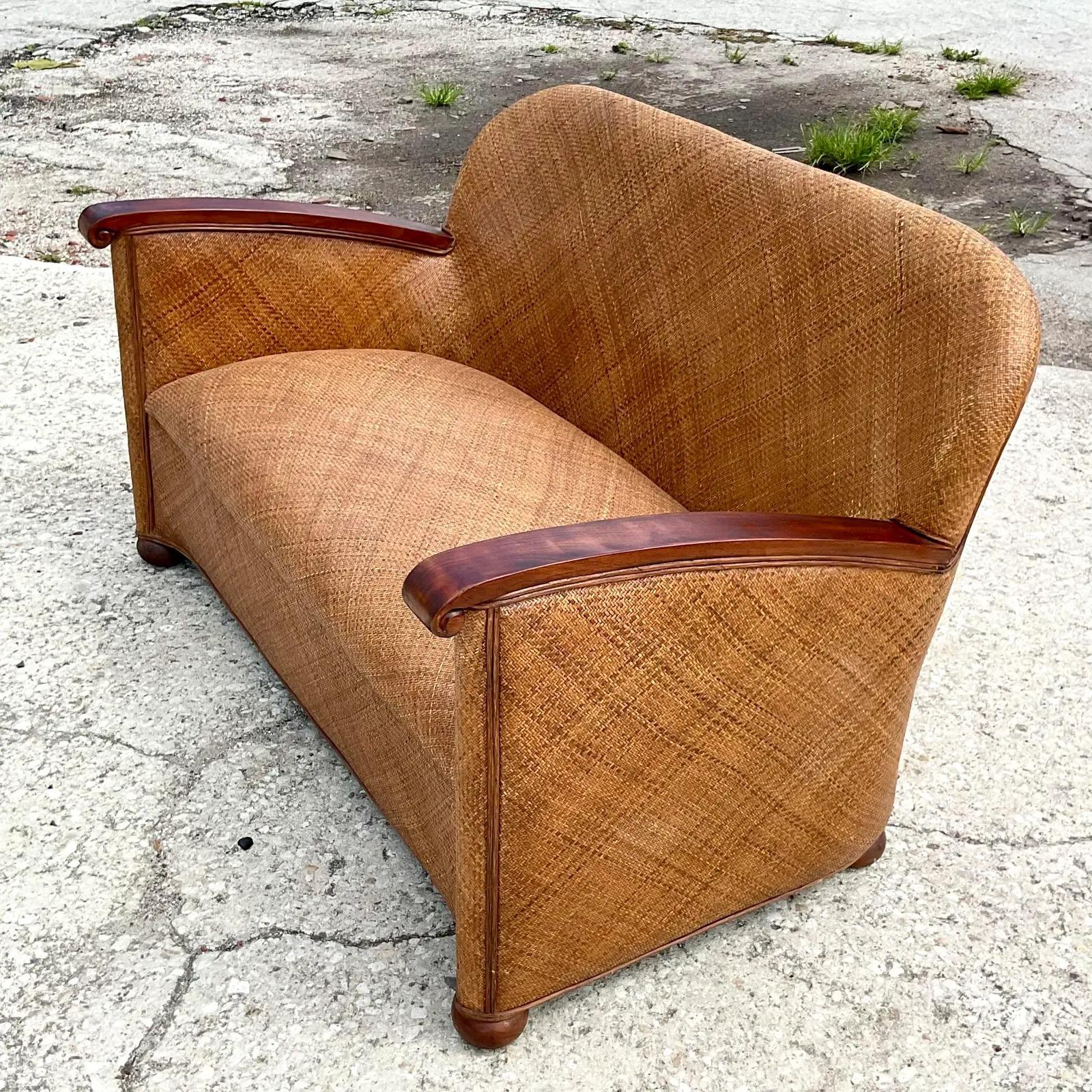 An amazing vintage Coastal sofa. Beautiful all over woven rattan upholstery and sleek wooden arms. A chic and polished look for your relaxed room. Acquired from a Palm Beach estate.