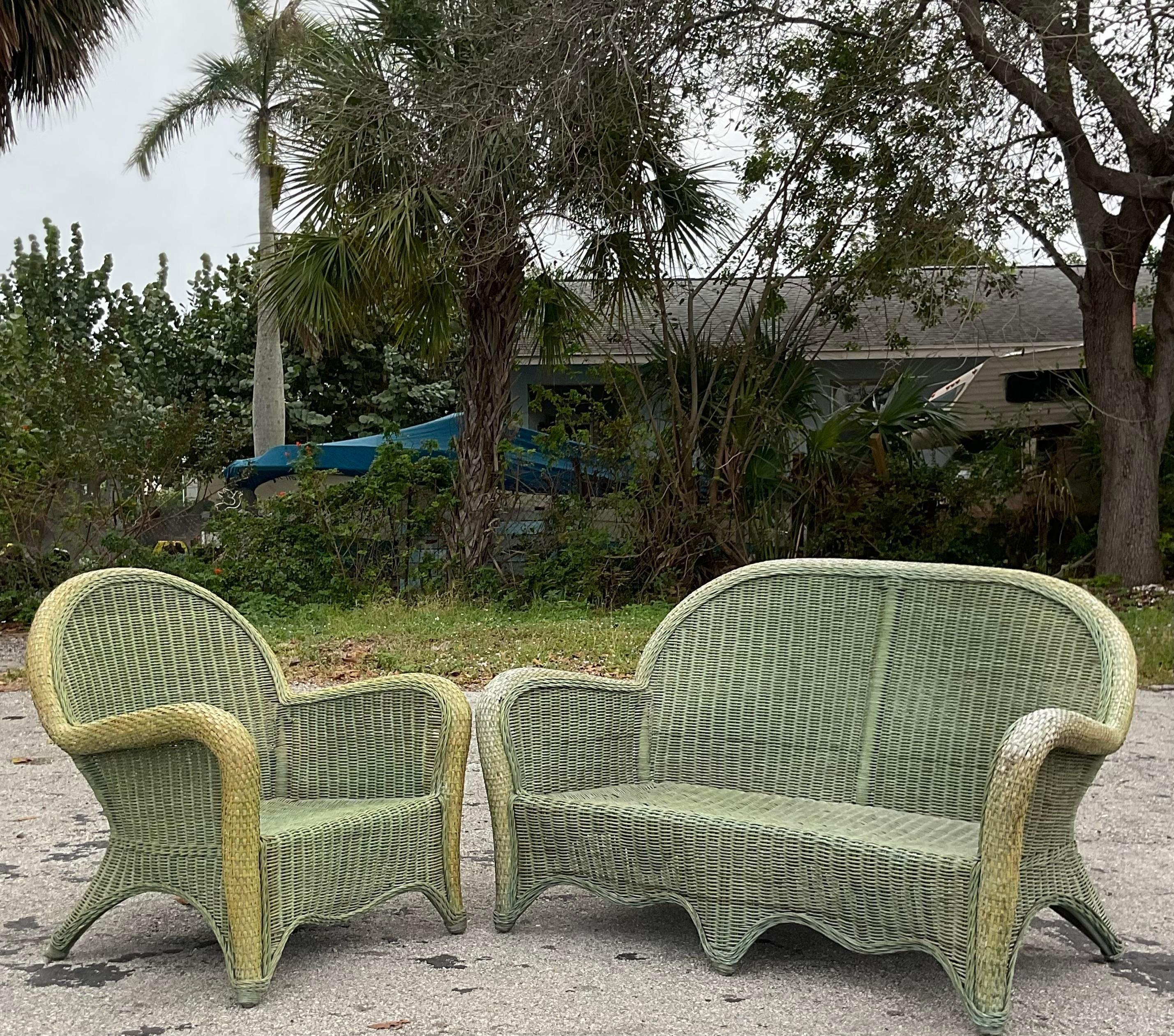A fabulous set of loveseat and chair. A chic woven rattan in a classic roll back design. A chic green color with a beautiful patina from time. Acquired from a Palm Beach estate.

Chair 30x22.5x33.5
