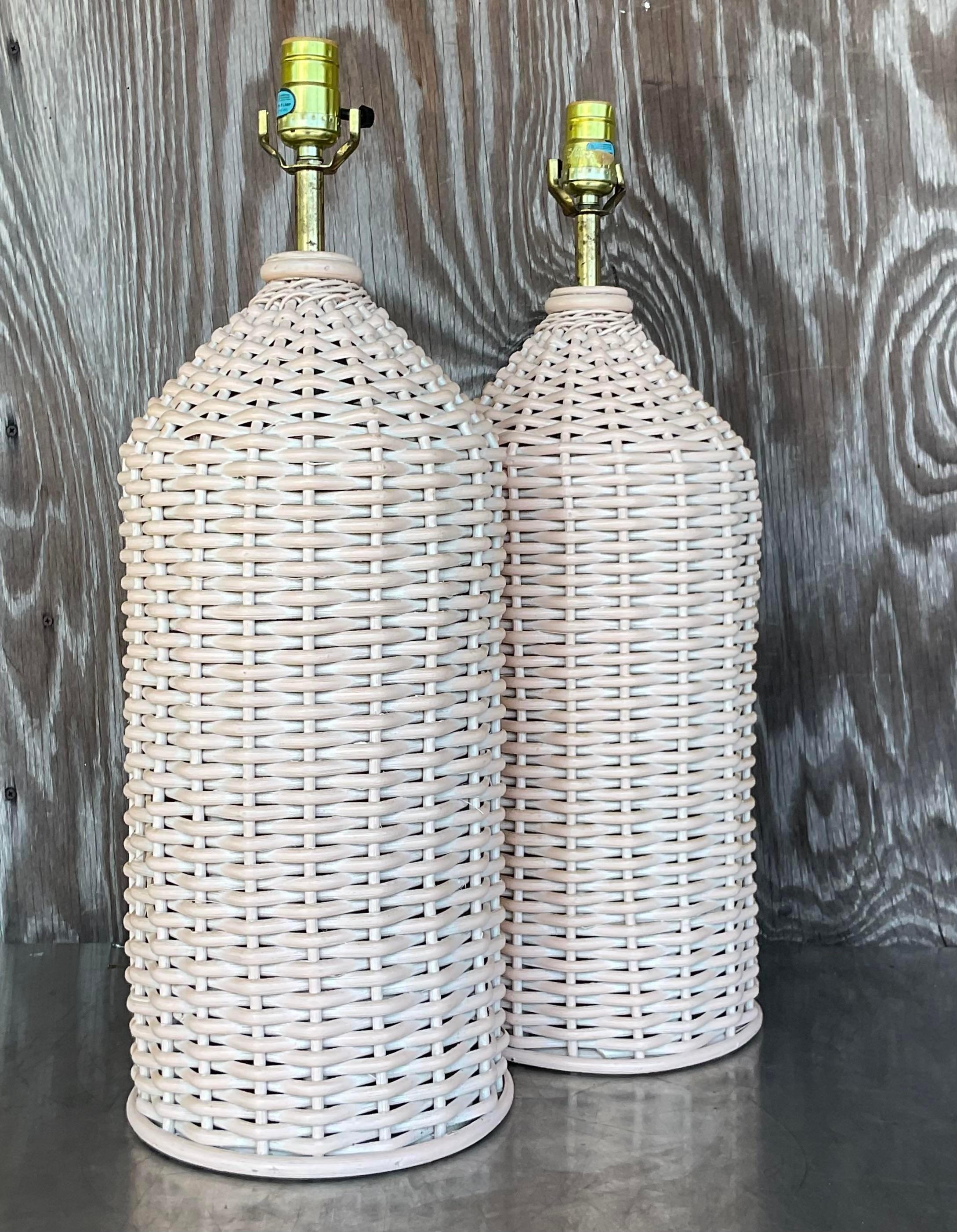 A fabulous pair of vintage Coastal table lamps. Chic woven rattan in a clean cylinder shape. A tan color with the tiniest bit of a pale pink cast. Acquired from a Palm a each estate.