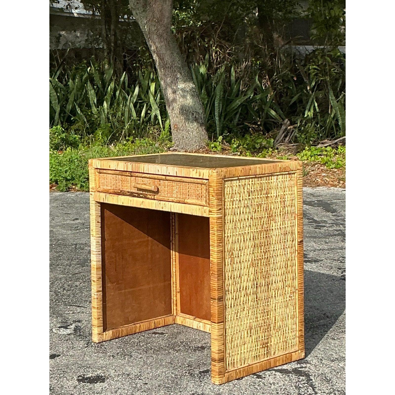 Eleganza costiera senza tempo con questo scrittoio vintage in rattan intrecciato, un pezzo di ottima fattura che emana calore e fascino naturale. L'intricata trama del rattan, incorniciata da dettagli in stile bambù, aggiunge un tocco di