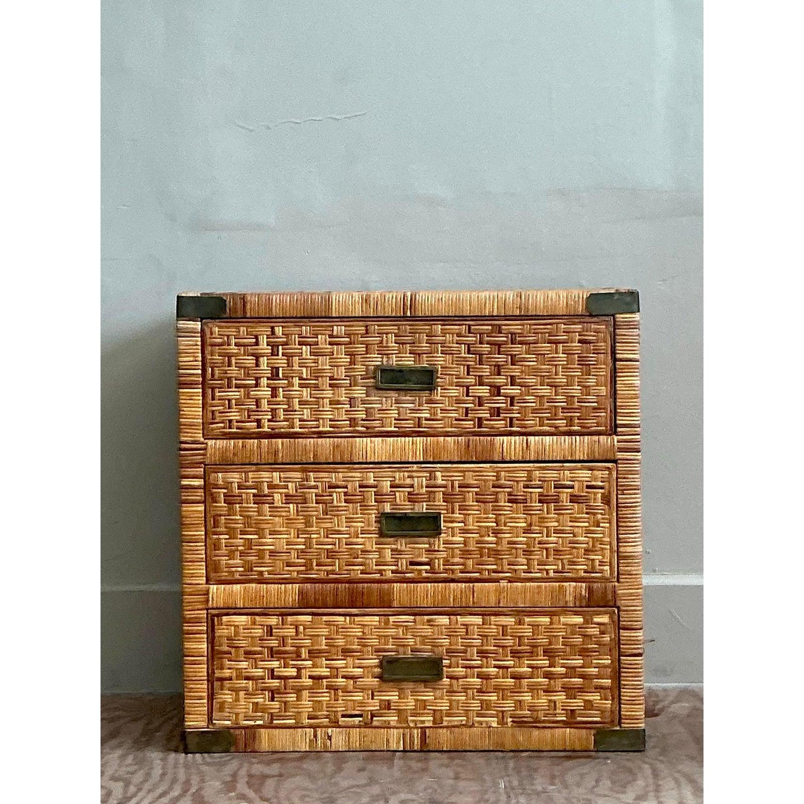 A superb vintage chest that exudes coastal elegance and incredible textural appeal. This handsome piece is completely enveloped in expertly wrapped rattan, with a beautiful basketweave top and campaign-style details like recessed brass pulls and