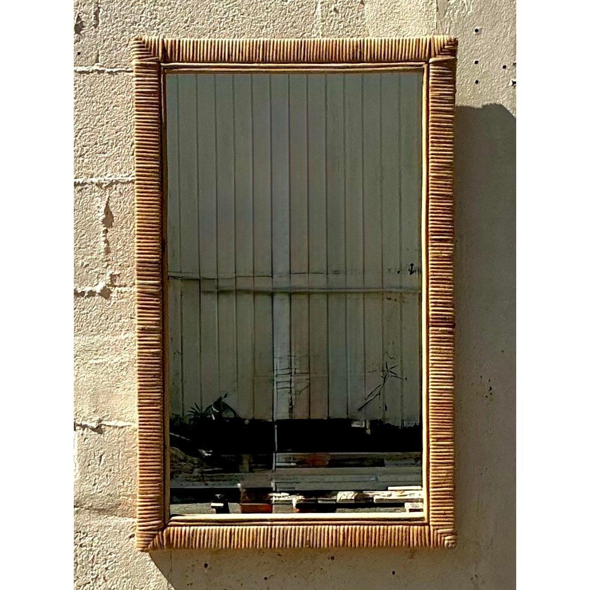Infondi nel tuo spazio il fascino fresco e costiero di questo specchio in rattan avvolto vintage. Caratterizzato da una cornice in rattan meticolosamente avvolta a mano in una calda tonalità miele, questo specchio rettangolare dona un senso di