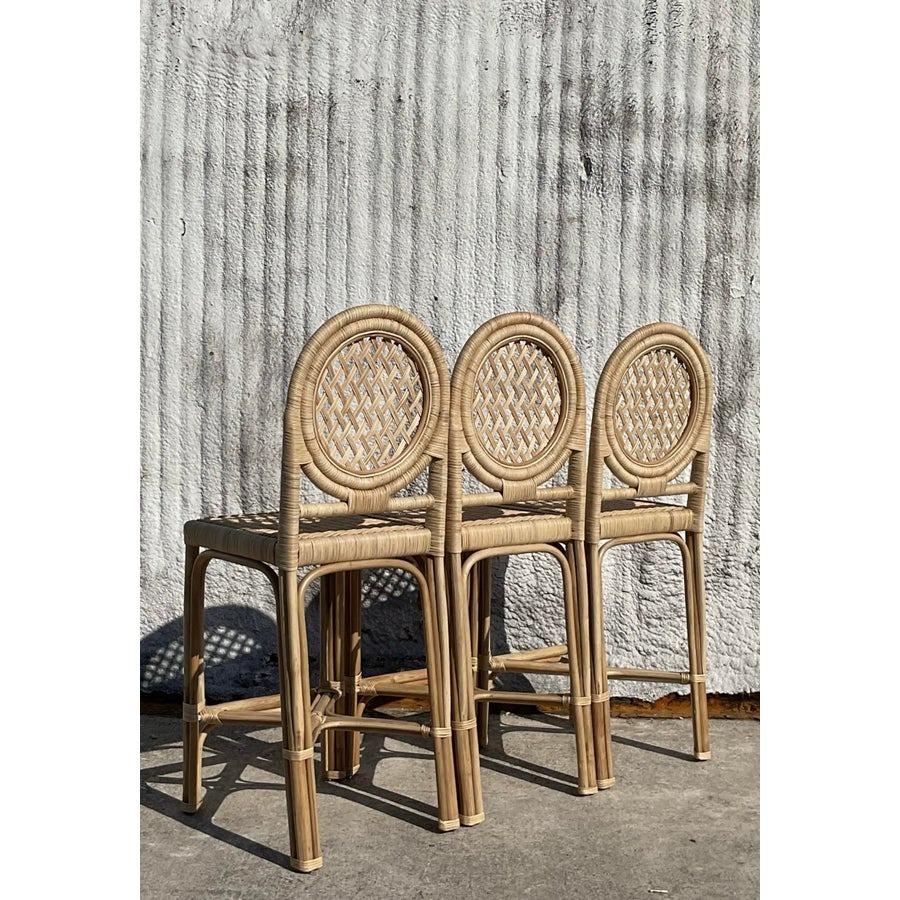 Enhance your bar or kitchen area with this charming set of three vintage coastal wrapped rattan trellis bar stools. Featuring a beautifully crafted circular trellis backrest and tightly woven rattan seats, these stools exude natural elegance and