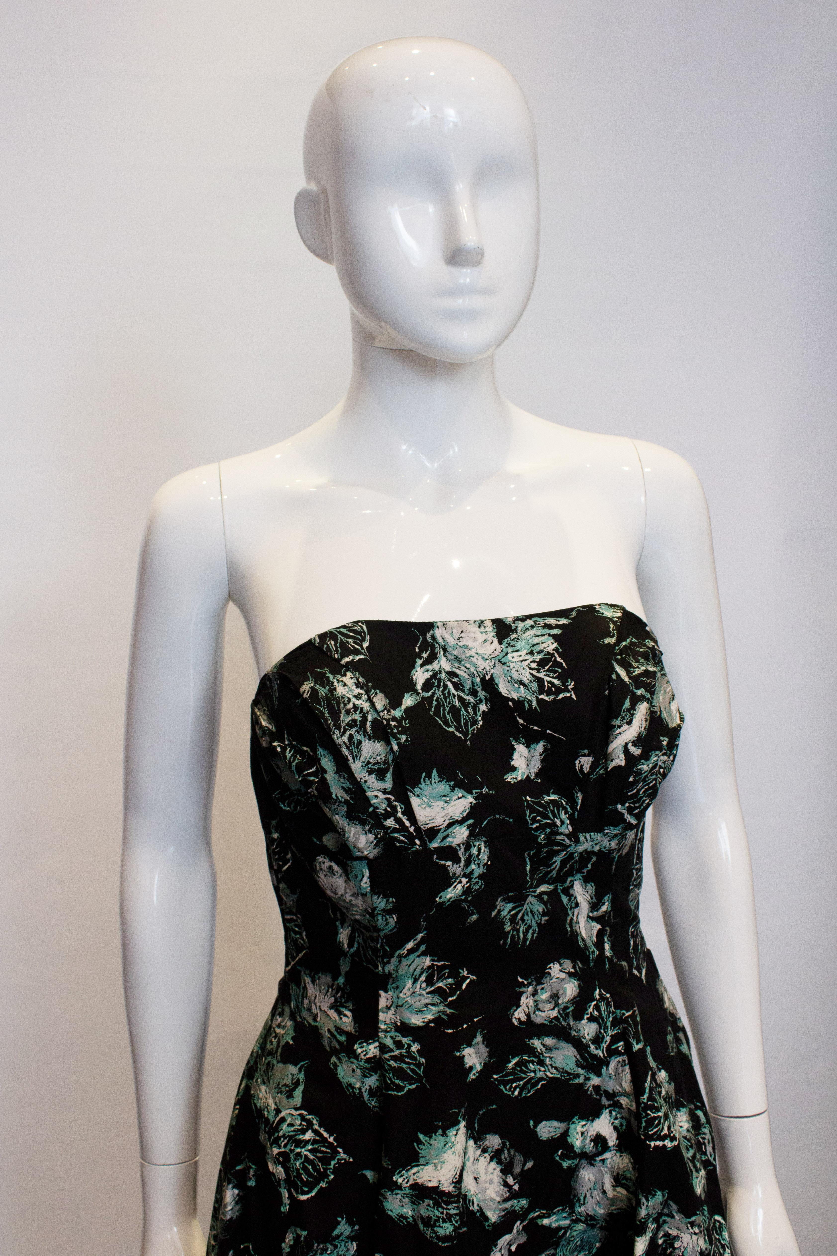 A fun vintage dress in a wonderful print of black, green, ivory and silver.
The dress is strapless, with boning in the bodice and a side zip opening.
Measurements: Bust 33'', waist 27'', length 38''