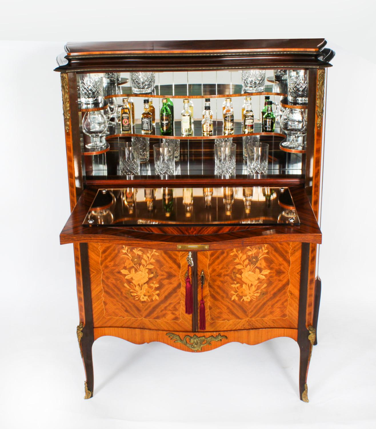 A 1930s burr walnut cocktail cabinet, in French 18th century style, with peach glass liner, mirrored interior, with a Maple & Co delivery tag to its back, some restoration carried out, Epstein of London, 95 by 42.5 by 117cm high.

This is a