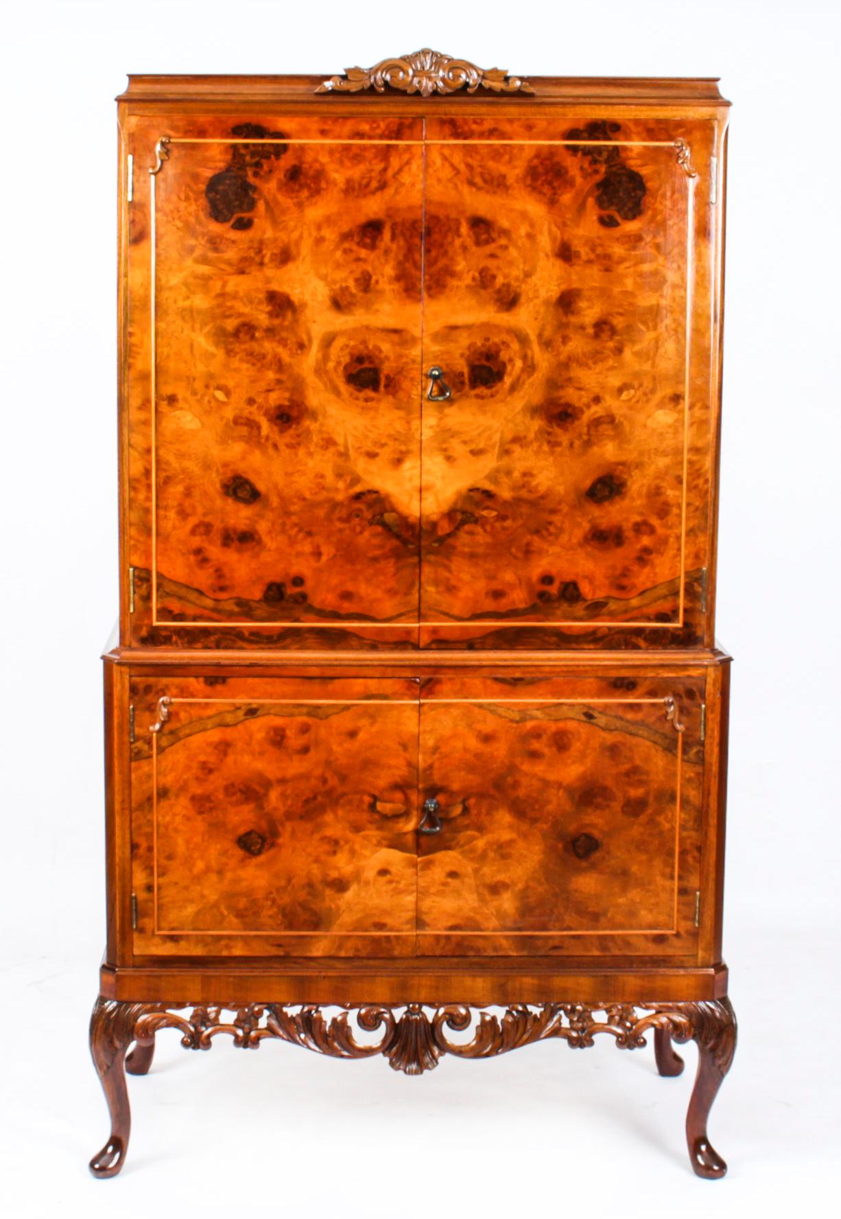 This is a fantastic vintage burr walnut cocktail cabinet with fitted and mirrored interior in the Queen Anne style, dating from the mid 20th century.


The upper part comprises a pair of doors that open to reveal a striking fitted mirrored and