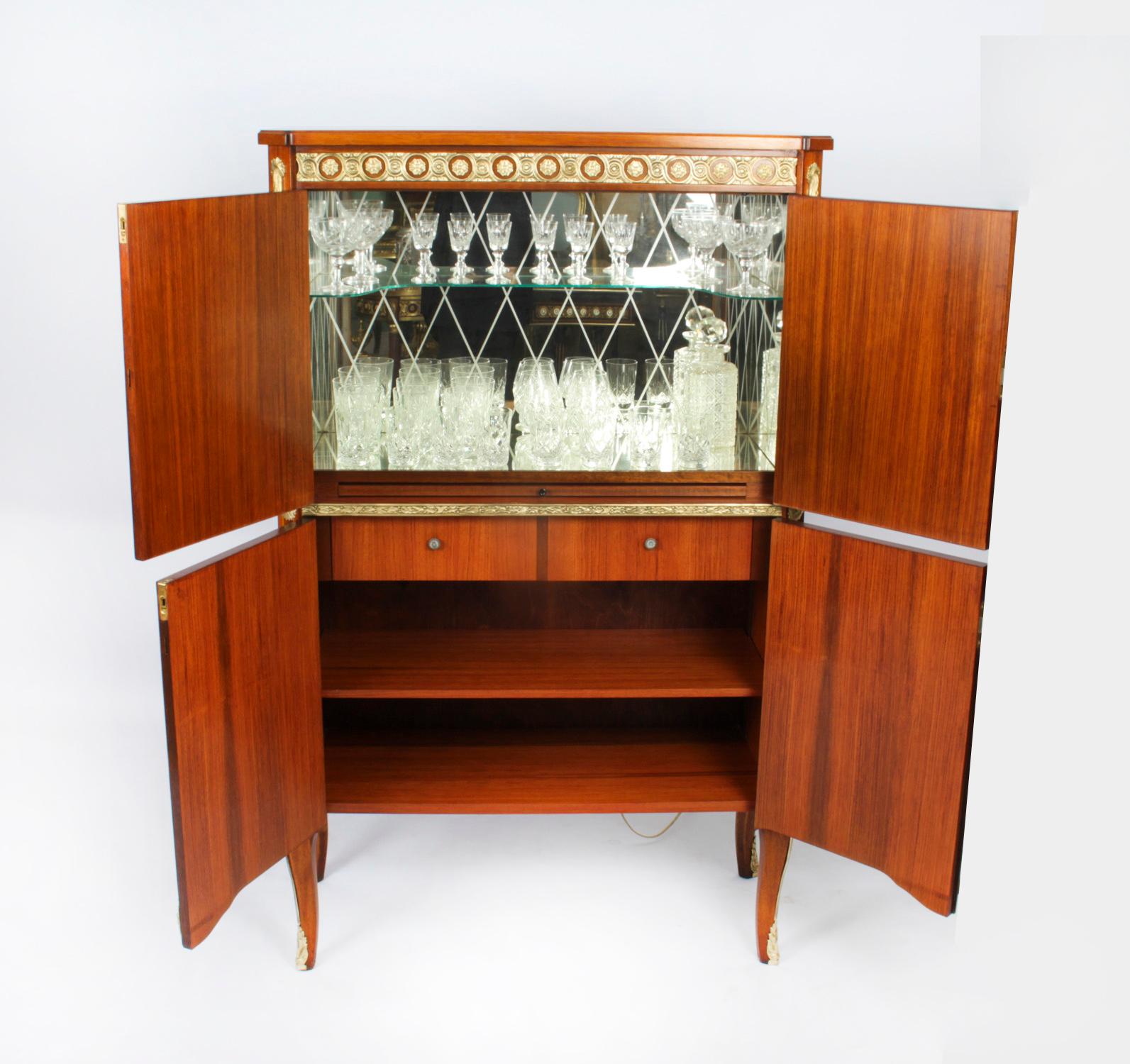 This is a fantastic vintage wood and marquetry cocktail cabinet with fitted mirrored interior and ormolu mounts, dating from the mid 20th Century.
 
The upper part comprises a pair of doors decorated with floral specimen marquetry that open to