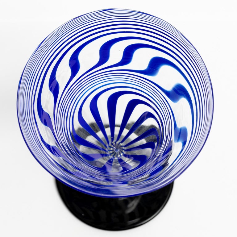 Circa 1920-1930s Bimini cocktail glass with two stirrers. The bowl of the glass features a blue swirl. The stem is further decorated with a capsule containing a dog figurine. One stirrer come in a chartreuse swirl, the other in a red swirl. Made in
