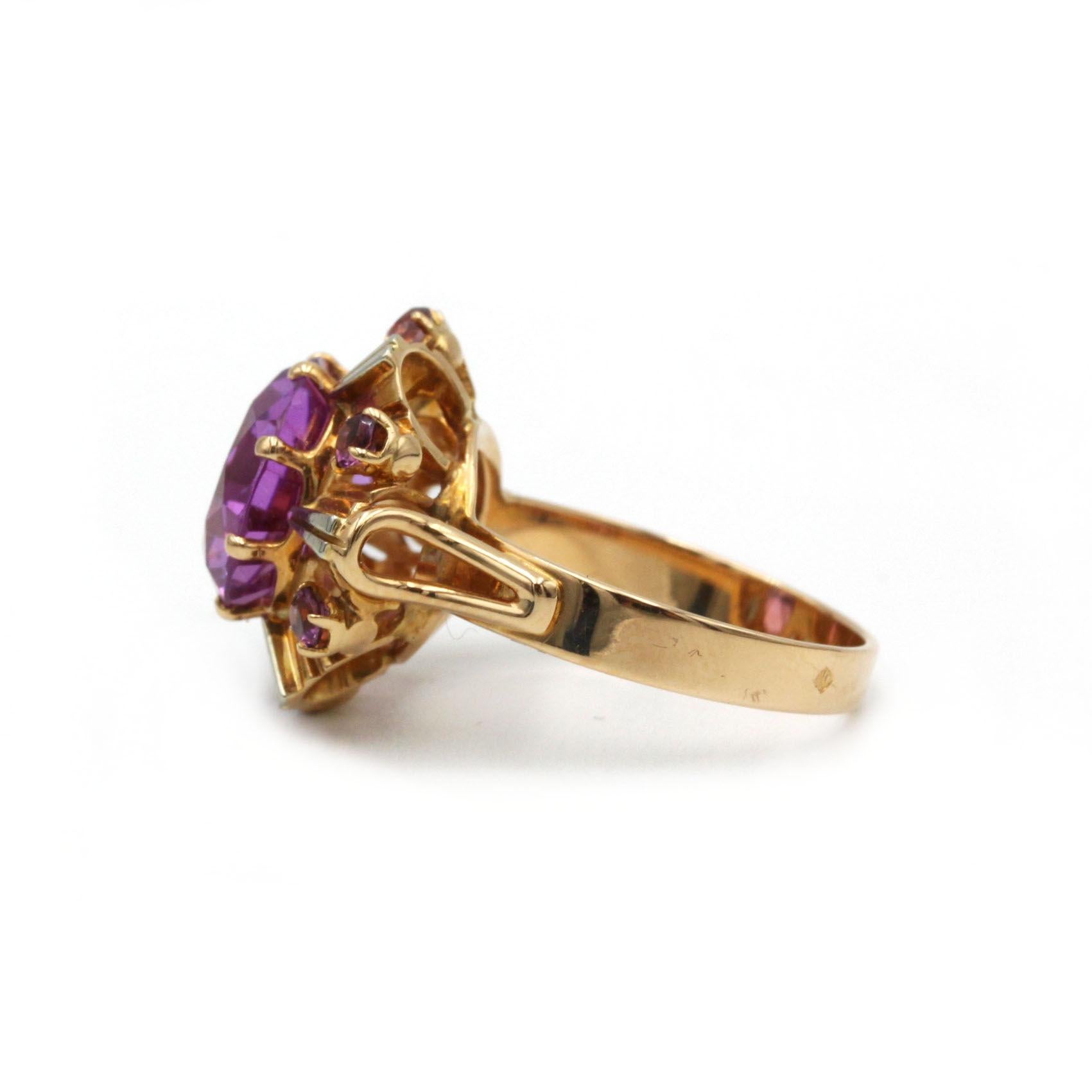 Adéntrate en la vibrante elegancia de los años 60 con este impresionante anillo de cóctel vintage. Elaborada en oro amarillo y blanco de 18 quilates (750‰), esta atrevida pieza muestra una cautivadora amatista central rodeada de seis amatistas más
