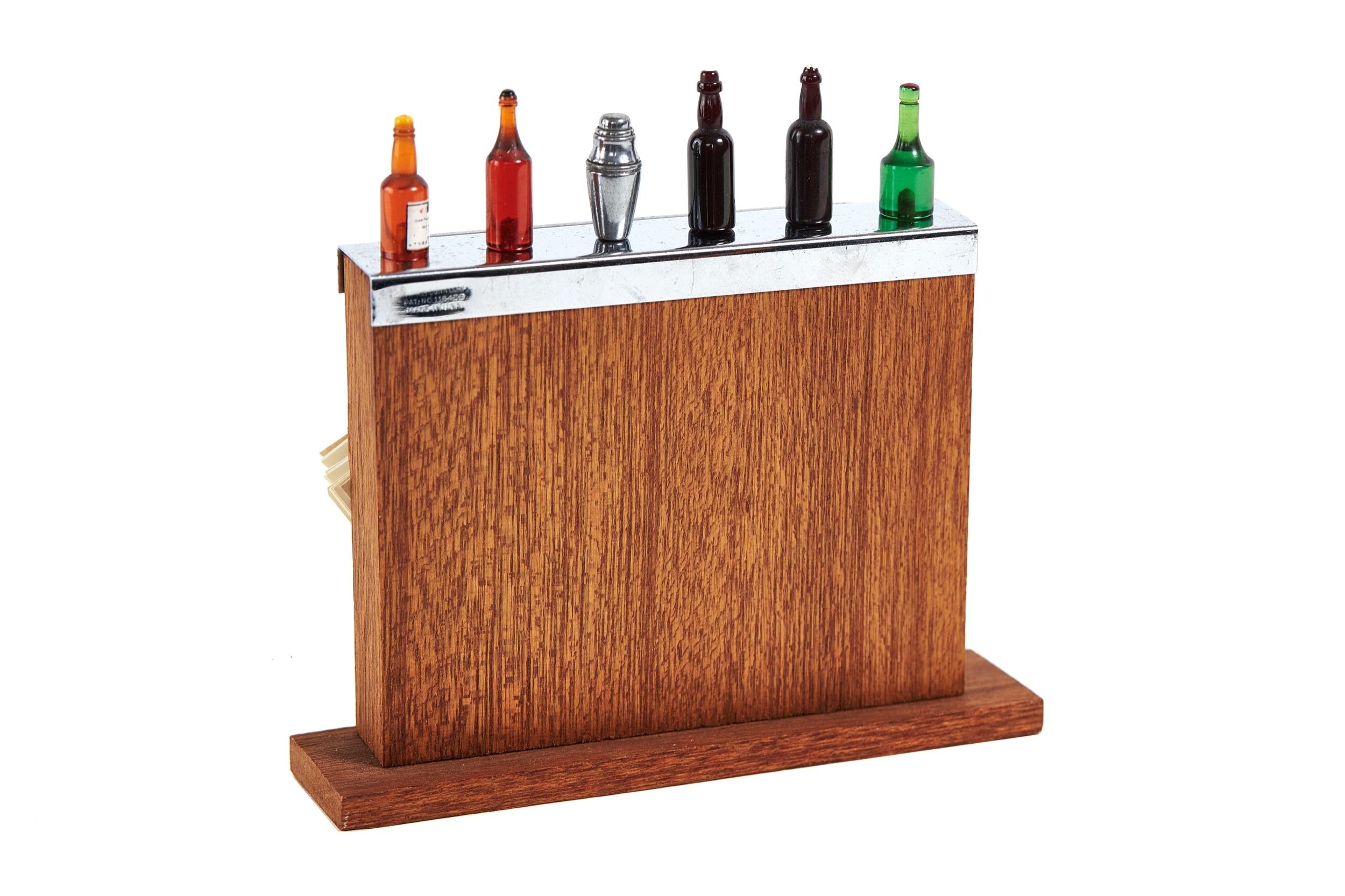 Vintage cocktail stick holder in the form of a bar
 by Harris Dunn circa 1940s
wood Bar with chrome capped top & rail, 
Holes in top  to hold 6 cocktail sticks in the form of :
 5 baklite shaped bottles & 1 Metal Cocktail Shaker
[labels are worn on