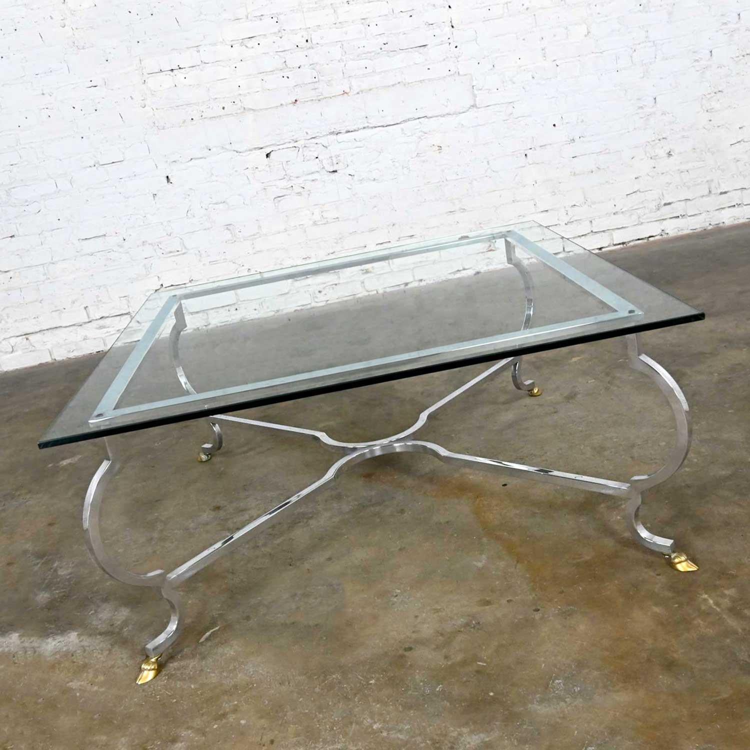 Stunning vintage Hollywood Regency ½ inch square glass top cocktail table with a polished aluminum base and polished solid brass hoof feet in the style of La Barge. Beautiful condition, keeping in mind that this is vintage and not new so will have