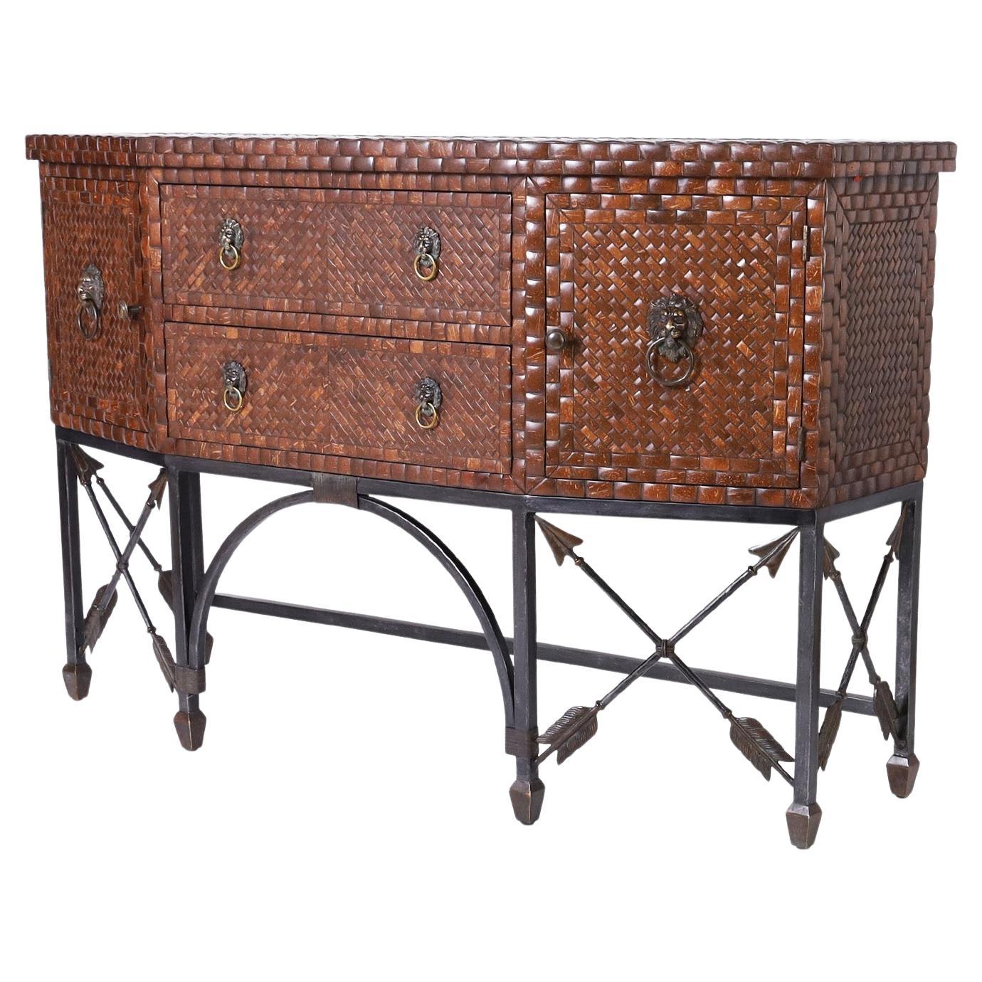 Impressive midcentury sideboard or server having a case with a bronze abstract mosaic top and polished coconut sides and front with two drawers and two doors having Classic lionhead hardware. The neoclassic iron base has crossed arrow motifs.