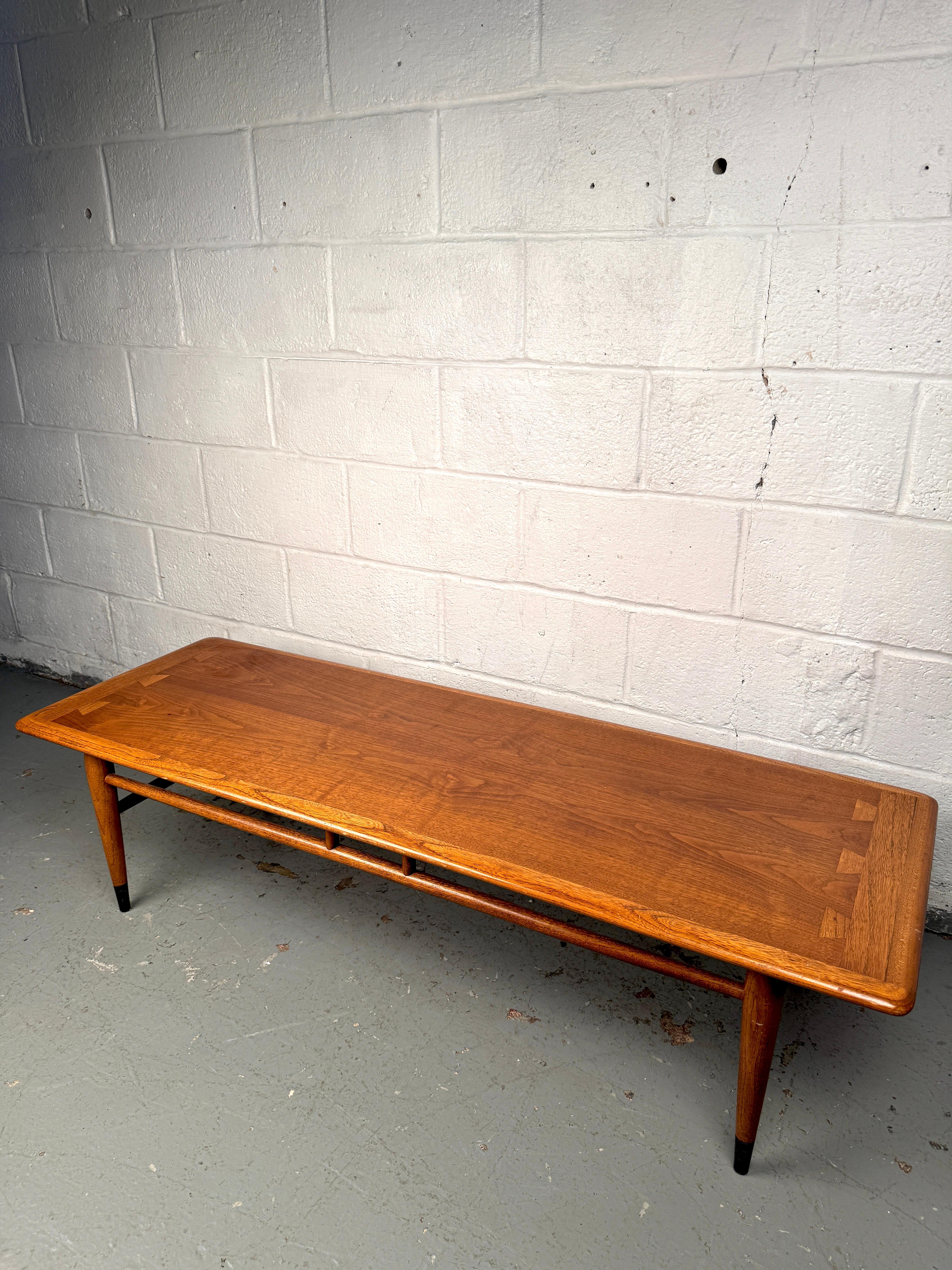 Una clásica mesa de centro moderna de mediados de siglo fabricada en teca, de líneas limpias y cálidos tonos de madera. Presenta un perfil minimalista con un diseño atemporal, que refleja el énfasis de la época en la funcionalidad y la elegancia