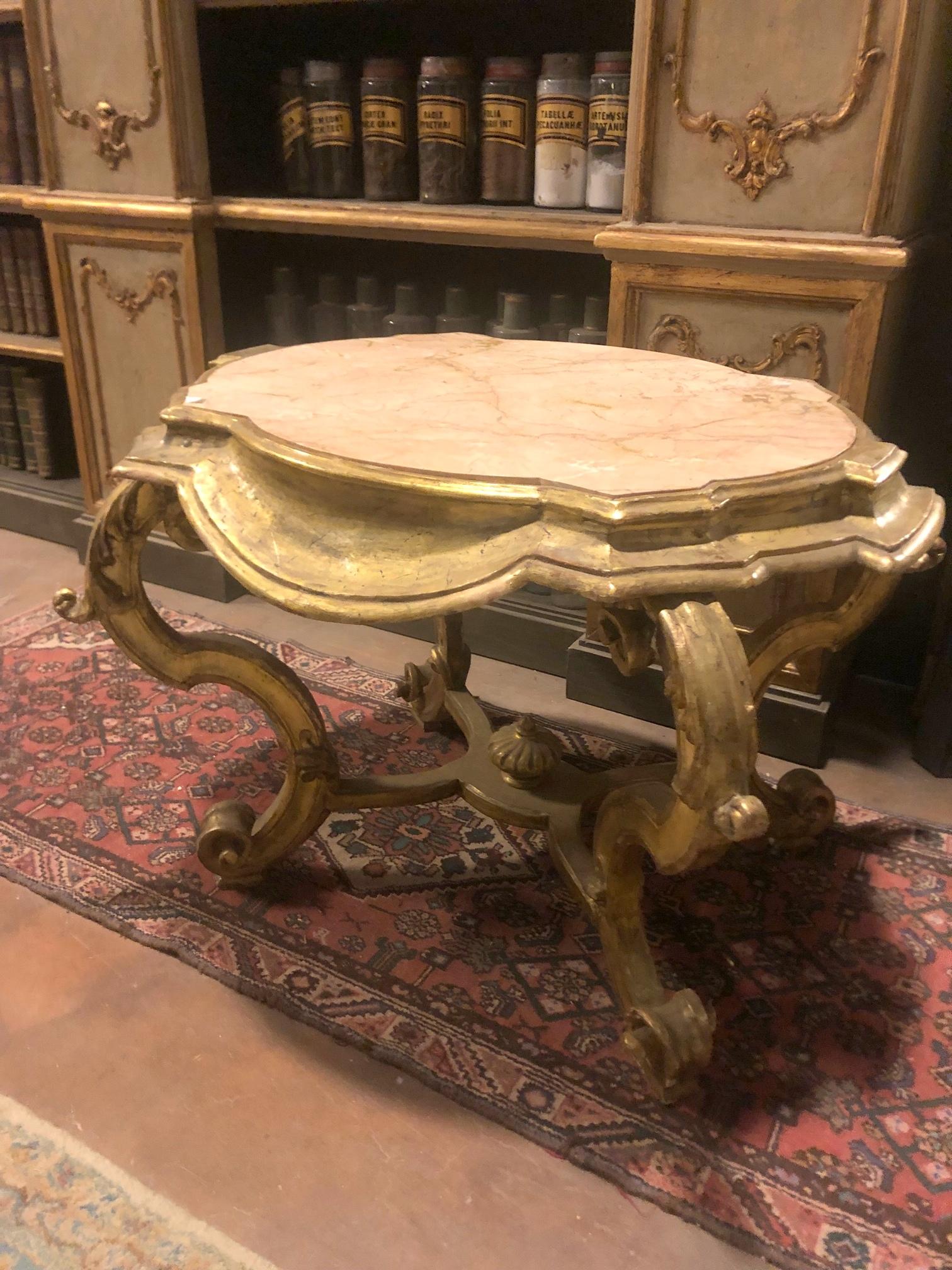 Vintage coffee table, small console table, richly carved with wavy legs, carved in gilded wood with pink marble top, built in Italy in the early 1900s, cm W 108 x H 75 x T 85.