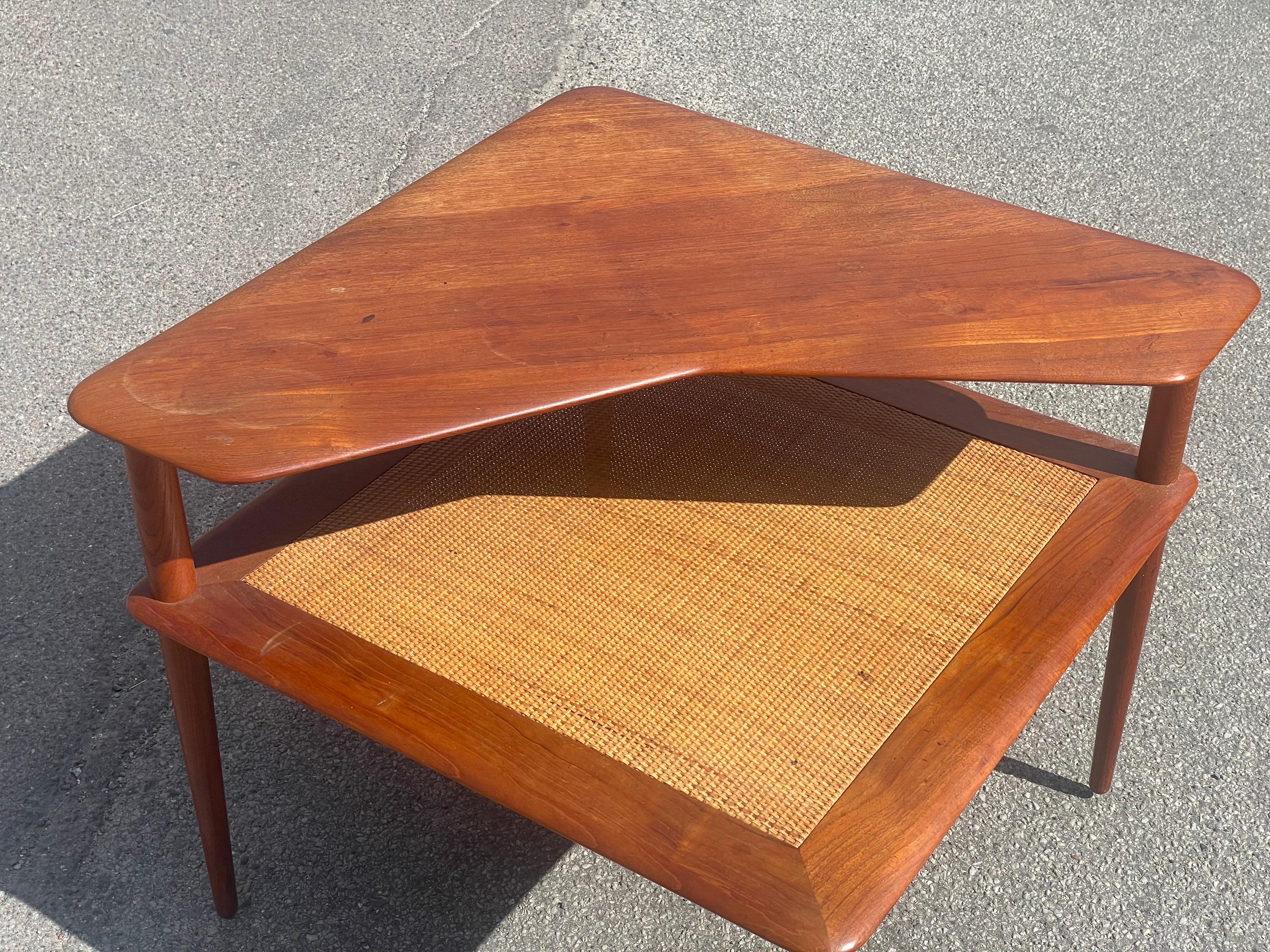 Original 1960s Danish design by Peter Hvidt & Orla Mølgaard-Nielsen. This corner table features a stunning teak veneer construction with a lower shelf crafted from braided bamboo, epitomizing timeless elegance and functional design.