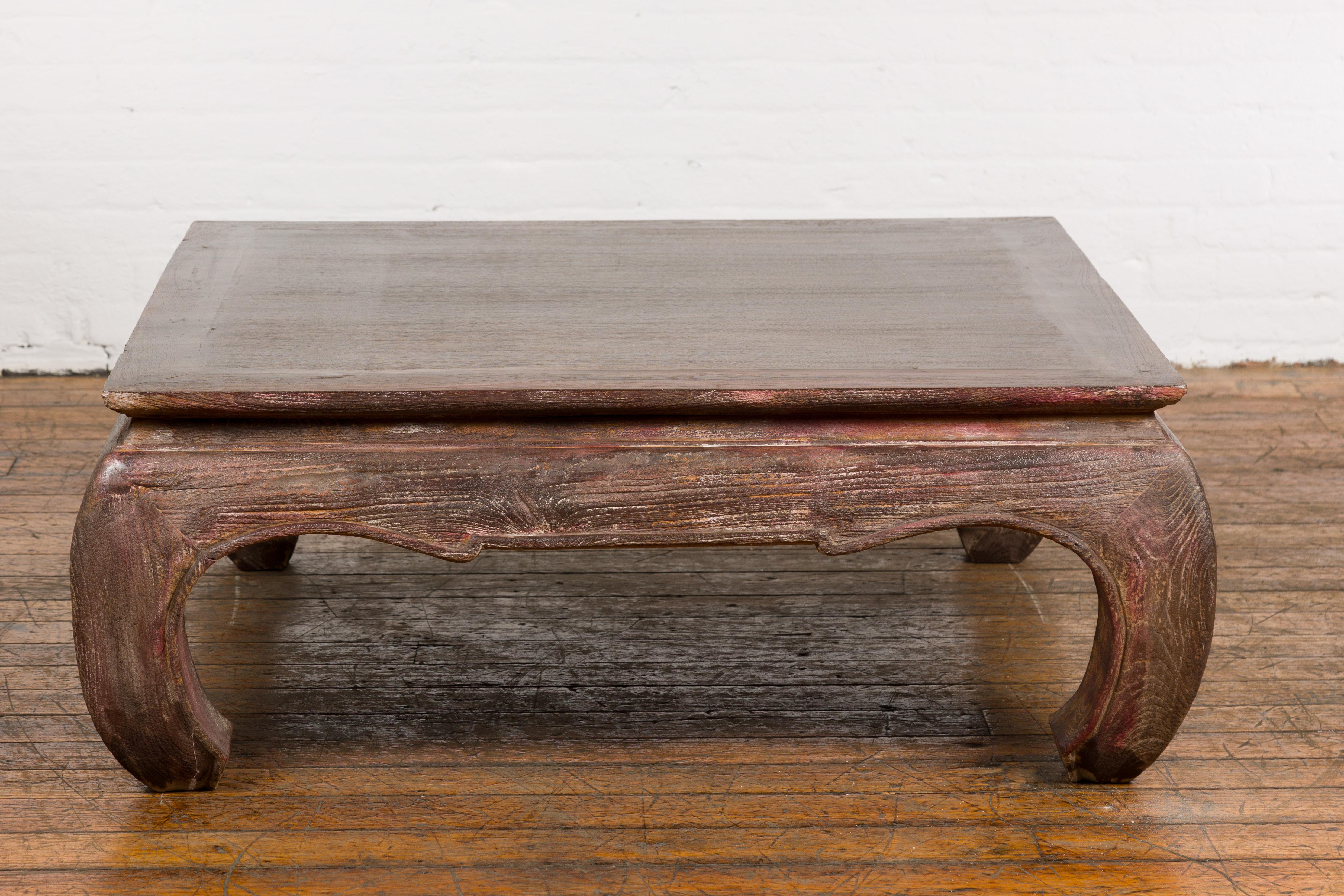 A vintage coffee table with chow legs, square top and distressed patina. Embrace the enduring appeal of Asian-inspired design with this vintage coffee table, a handsome piece of furniture that harmoniously blends antique charm and contemporary