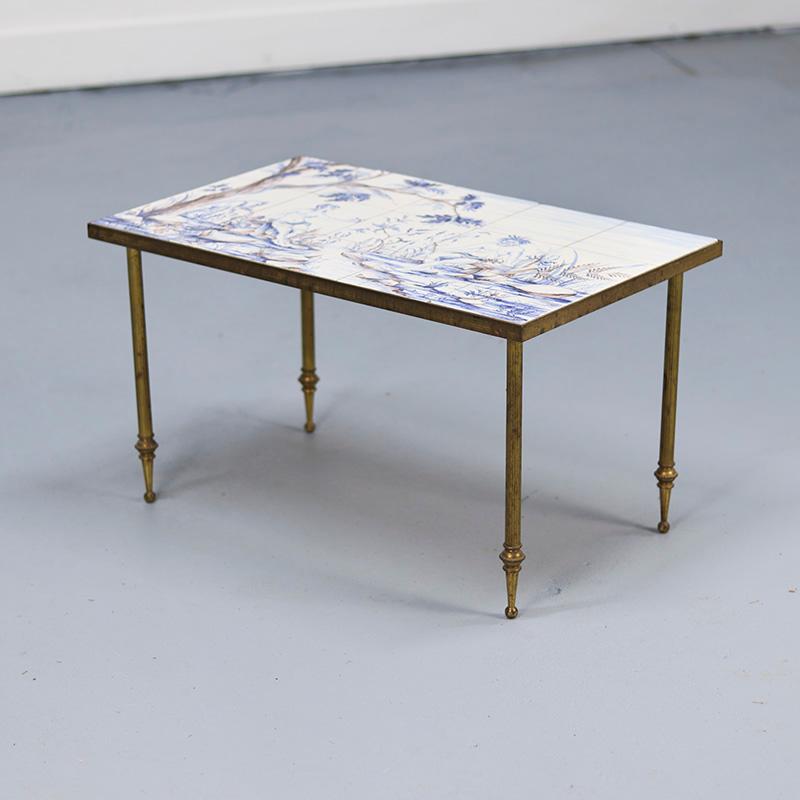 Une table basse unique dotée d'un cadre en laiton et d'un plateau exceptionnellement incrusté de carreaux peints à la main. Les carreaux représentent une scène biblique d'Adams et d'Ève et sont signés, bien qu'aucune autre information sur l'artiste