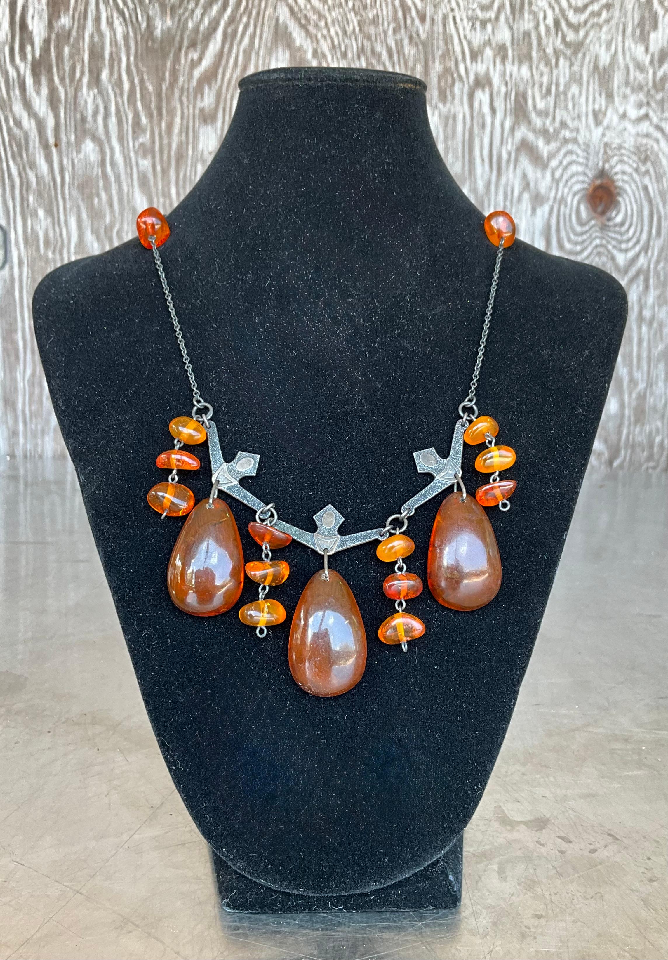 Entra nel calore dei secoli passati con questa straordinaria collana di ambra cognac vintage, un pezzo di qualità che cattura la bellezza grezza dell'ambra naturale e la raffinata eleganza della lavorazione artigianale dell'argento. Questa collana
