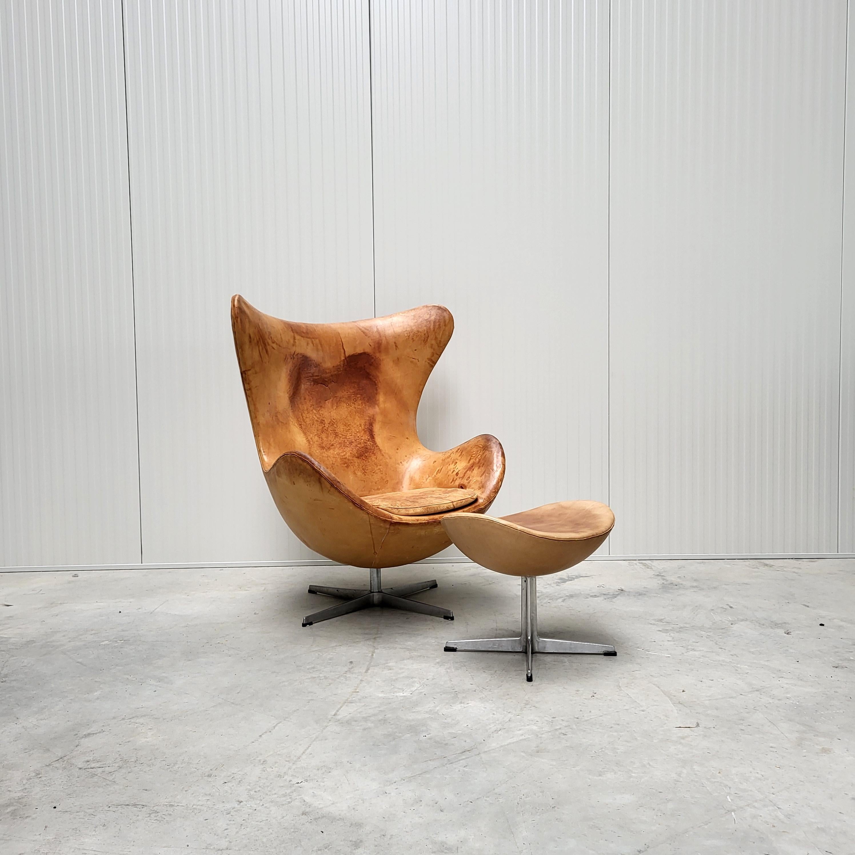 Cette très rare édition 70s de la chaise Egg et de l'ottoman a été conçue dans les années 50 par Arne Jacobsen pour l'hôtel SAS à Copenhague et produite par Fritz Hansen vers 1979/1980. Le fauteuil Egg est revêtu d'un cuir semi-aniline très fin.

La